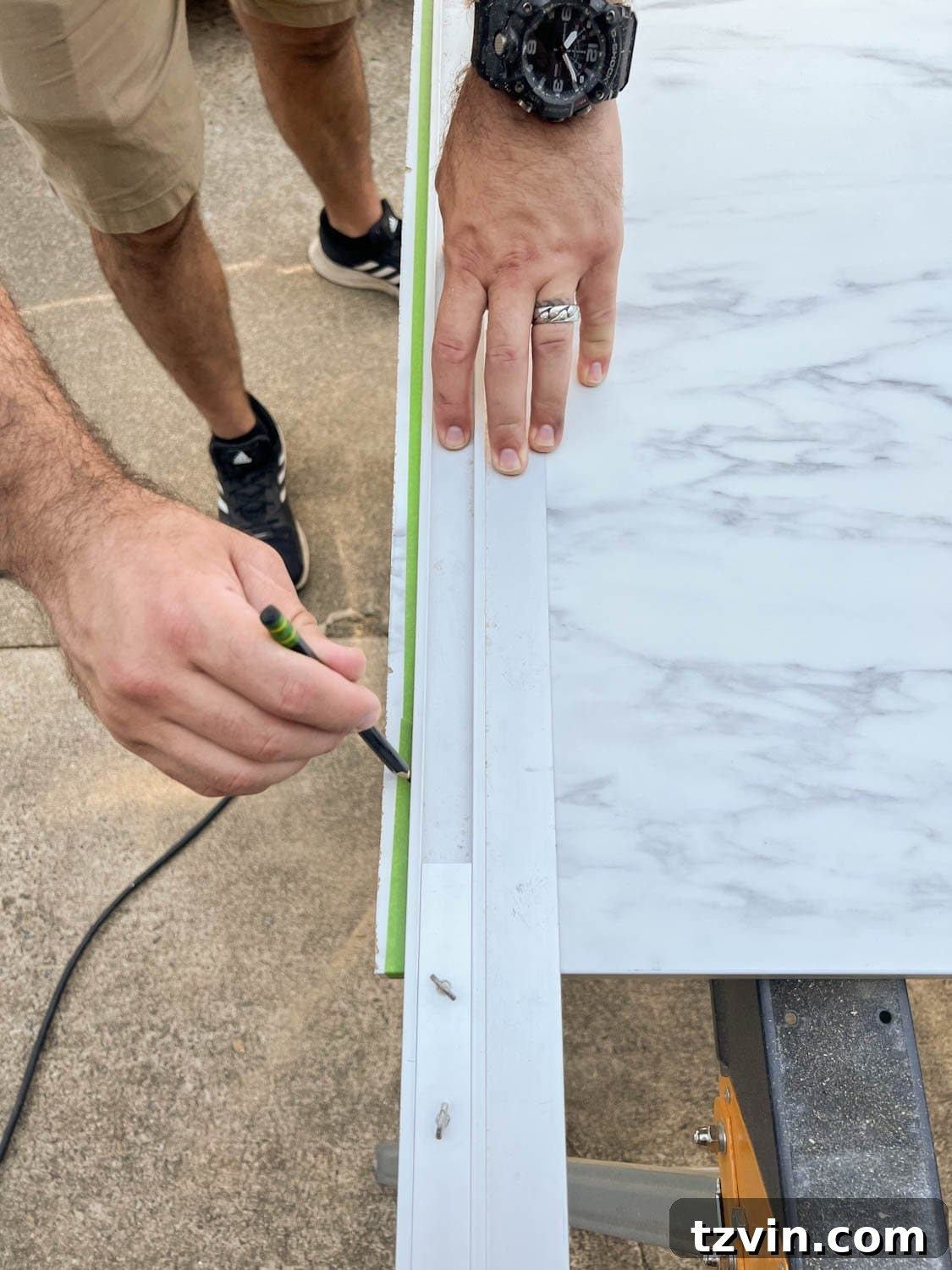 DIY Faux Marble Dining Table: Instant Luxury in Under an Hour 6 marking a straight edge on masking tape on laminate faux marble countertop to be cut, ensuring precision