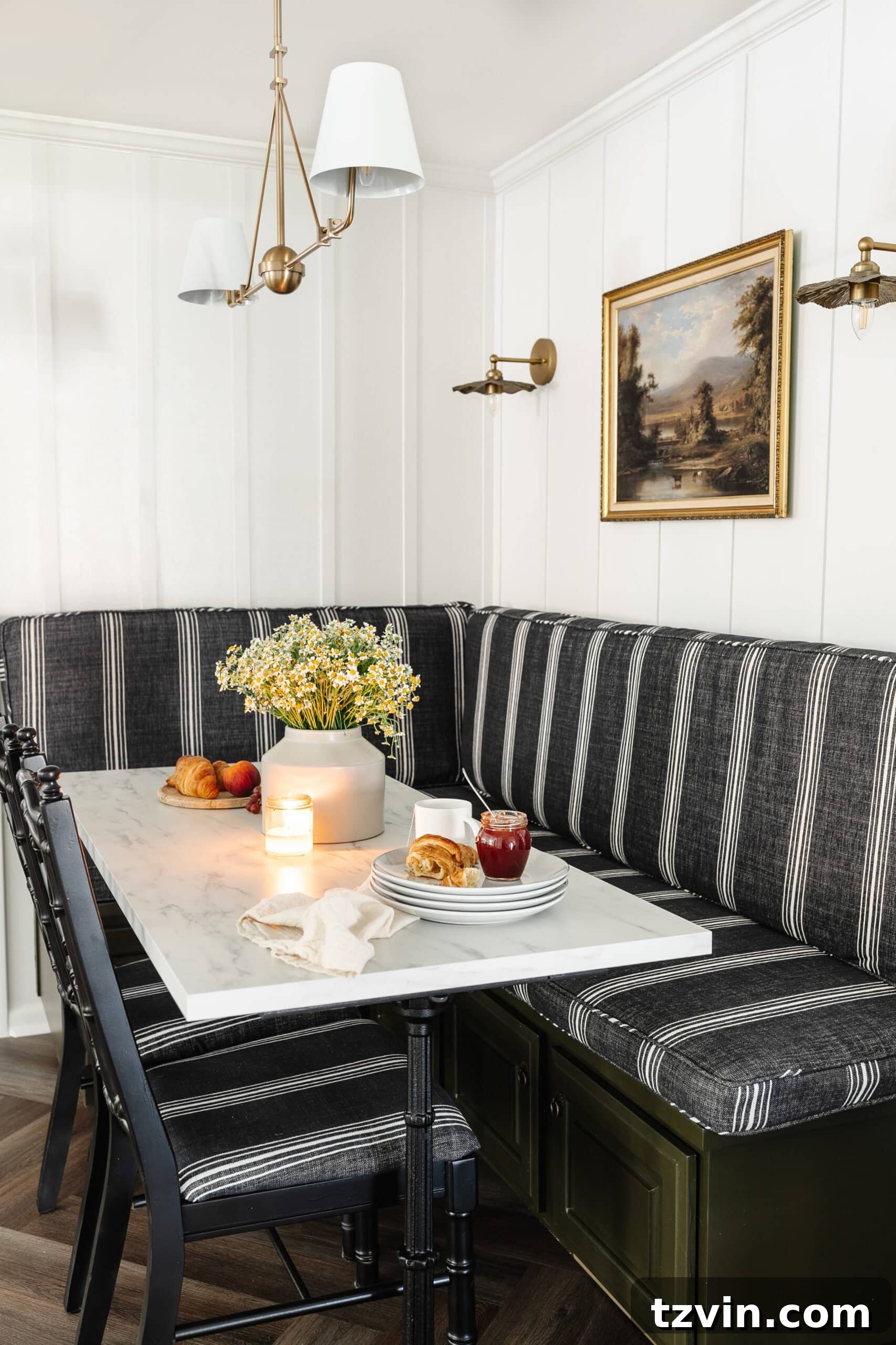 Chic Parisian Morning Retreat 11 Stylish charcoal striped booth in a corner breakfast nook, illuminated by a brass chandelier and wall sconces, centered around a beautiful marble dining table