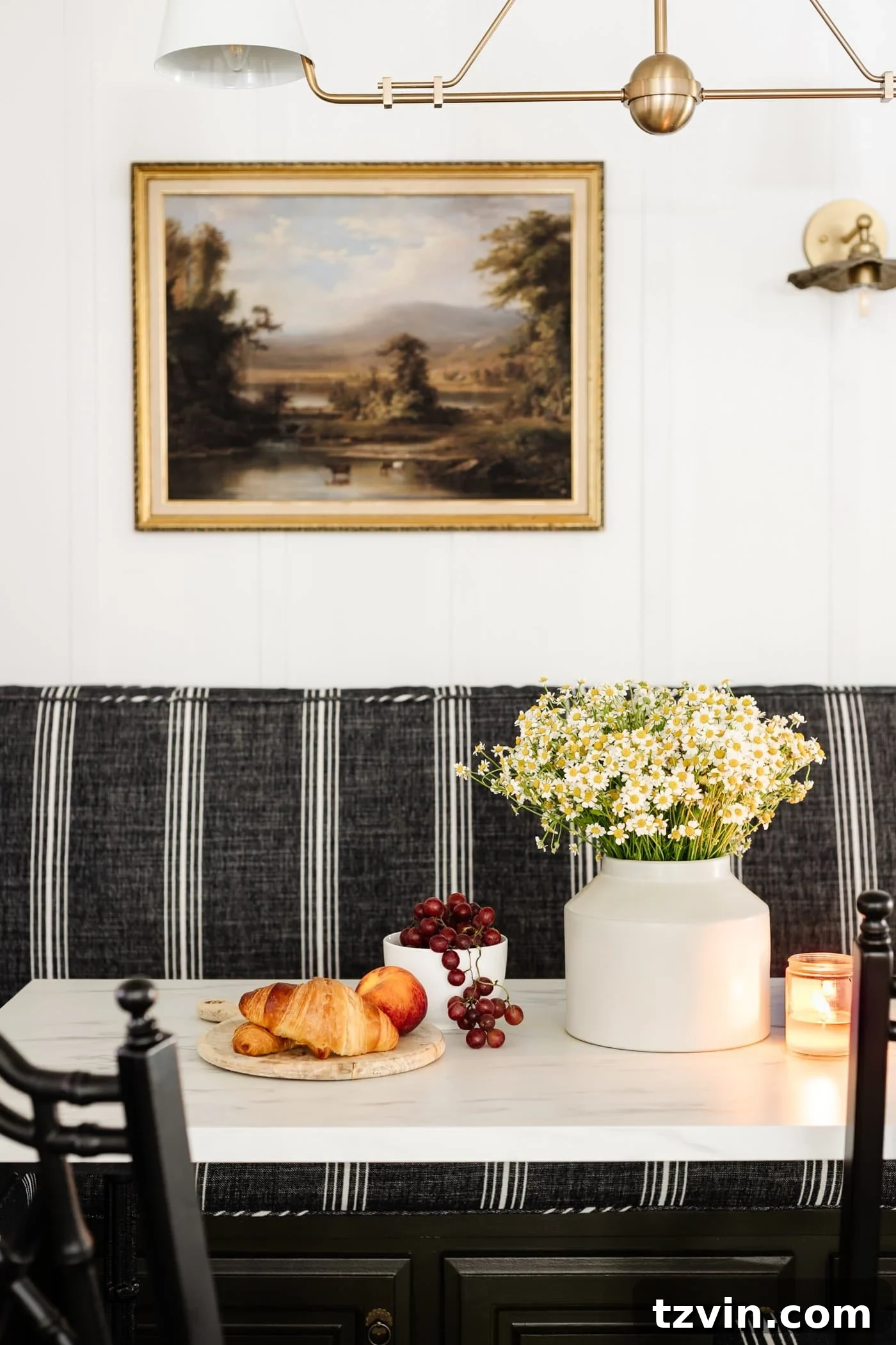 Chic Parisian Morning Retreat 15 Beautiful marble dining table adorned with a fresh vase of daisy flowers, a rustic serving board of croissants, and a bowl of ripe grapes, creating an inviting breakfast scene