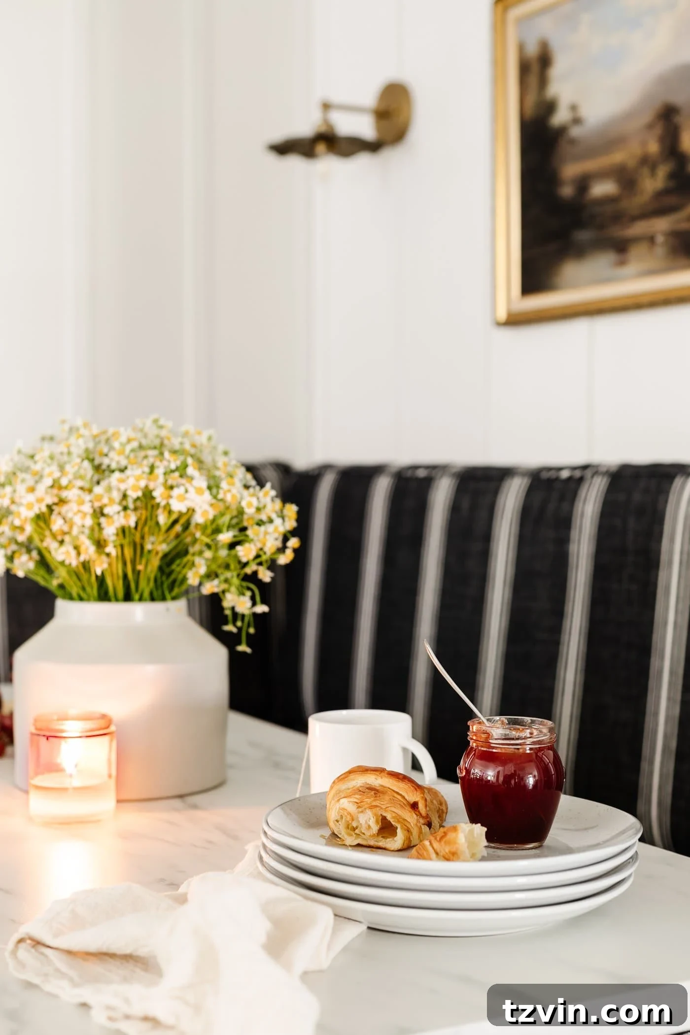 Chic Parisian Morning Retreat 16 Elegantly stacked plates on a marble dining table, beautifully arranged with a vase of fresh flowers and other charming breakfast decor elements