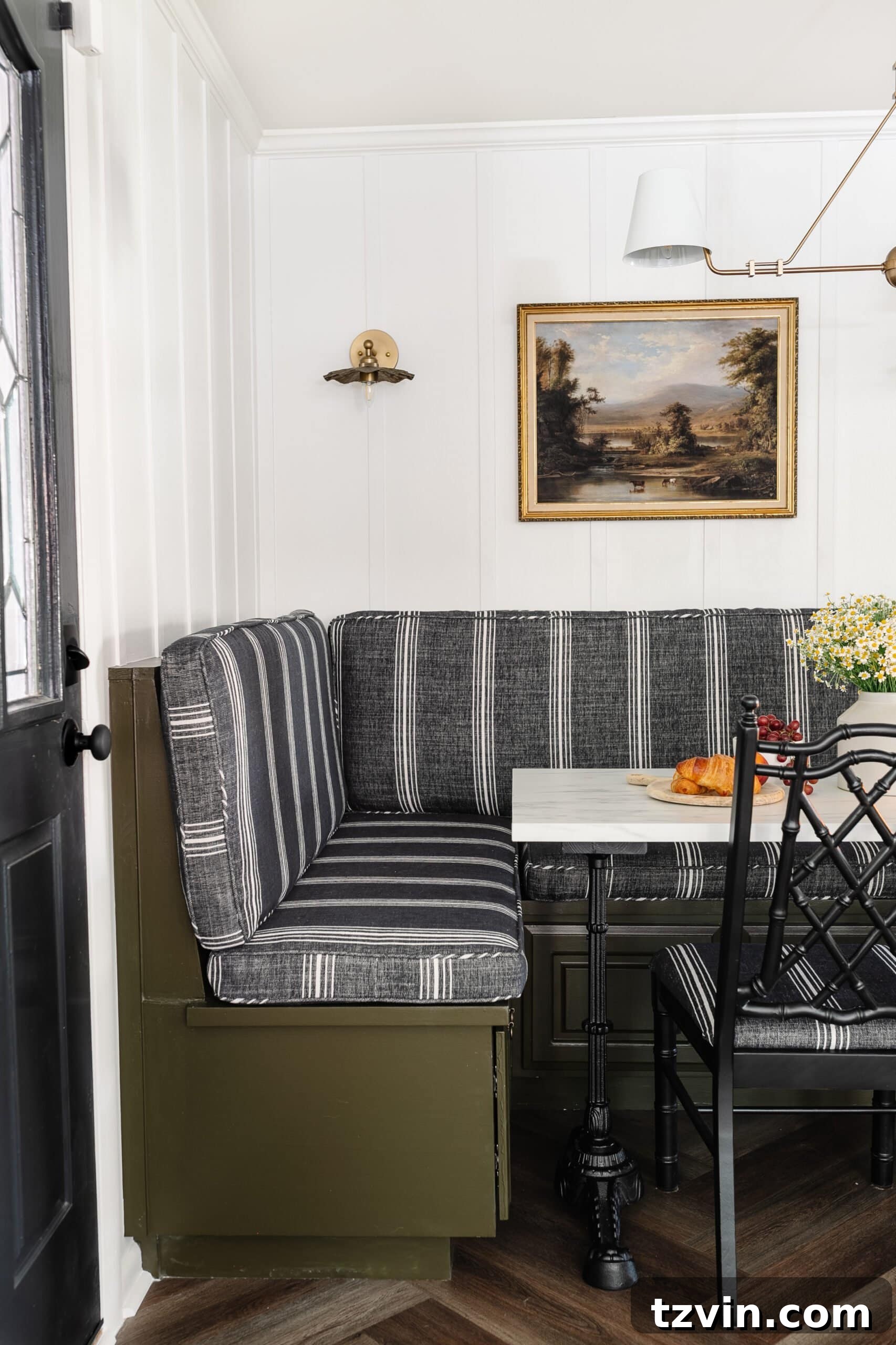 Chic Parisian Morning Retreat 8 After photo of the banquette bench featuring new striped charcoal cushions, painted in olive green, set against crisp white batten walls and adorned with an antique landscape oil painting