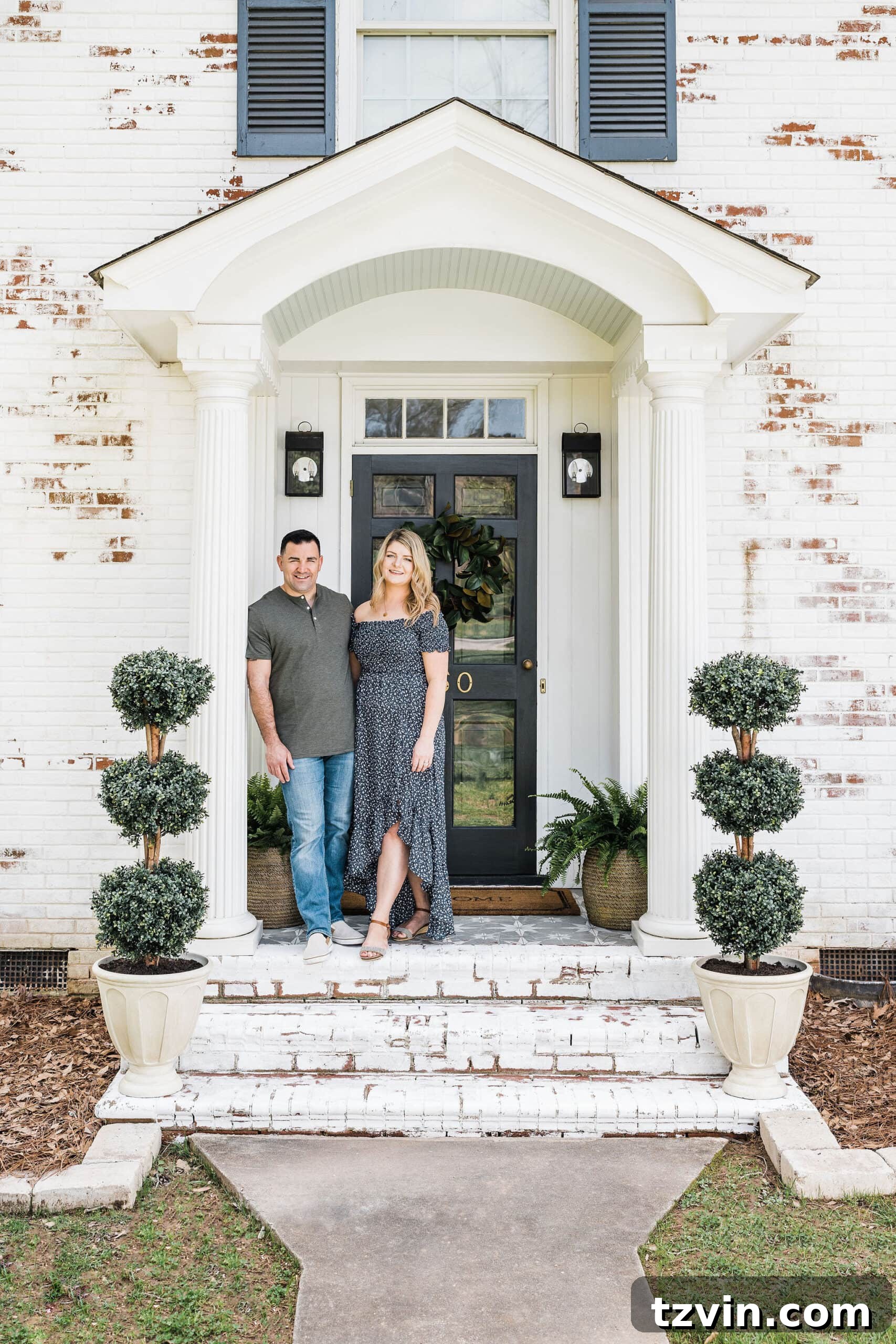 Freshly limewashed brick front porch stoop of a colonial house, adorned with elegant boxwood topiaries, radiating a bright and inviting curb appeal.