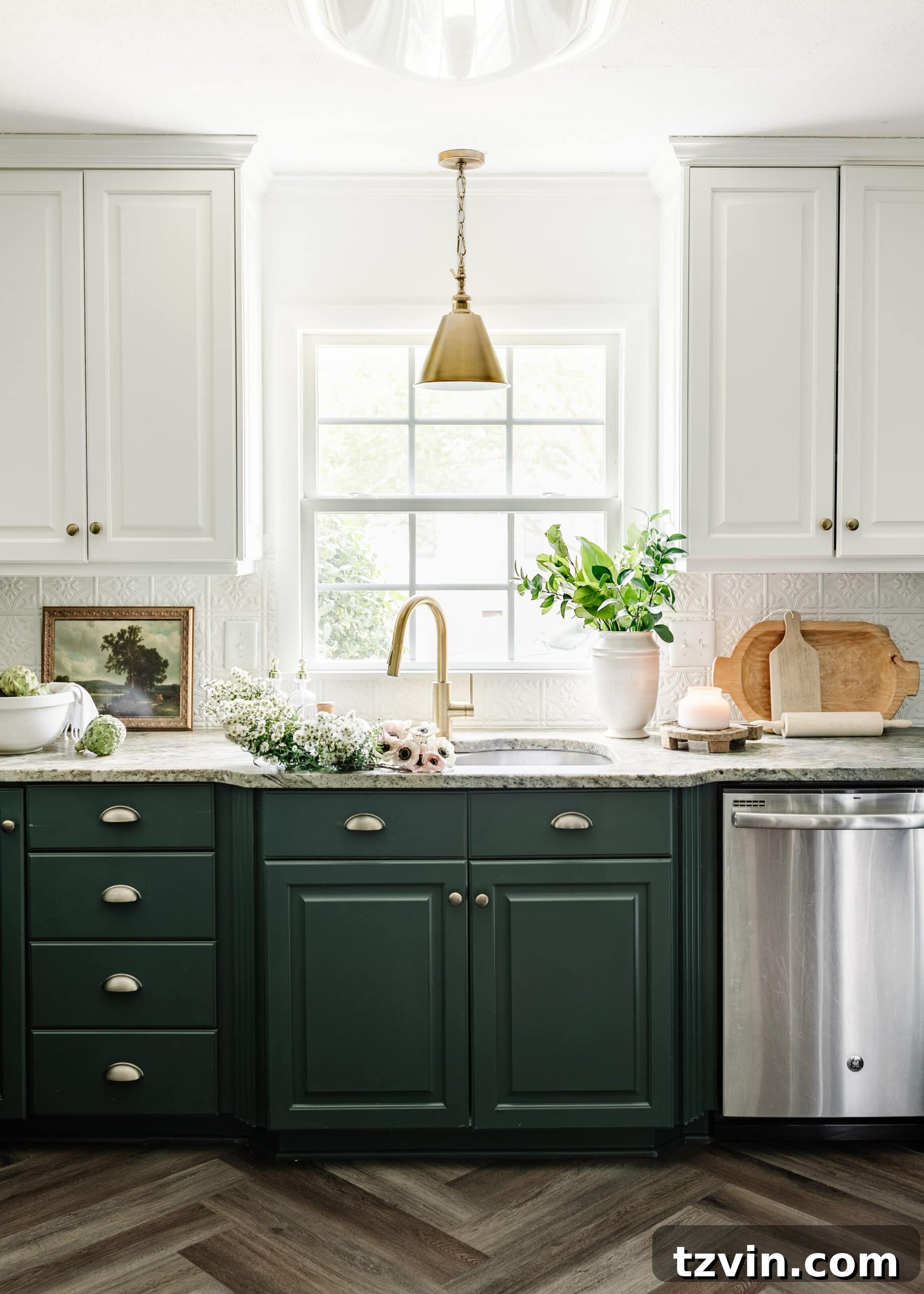 A charming cottagecore kitchen featuring white and green cabinets, elegant herringbone wood floors, a stylish brass faucet, a statement brass pendant light, and warm brass hardware, creating a serene and inviting atmosphere.