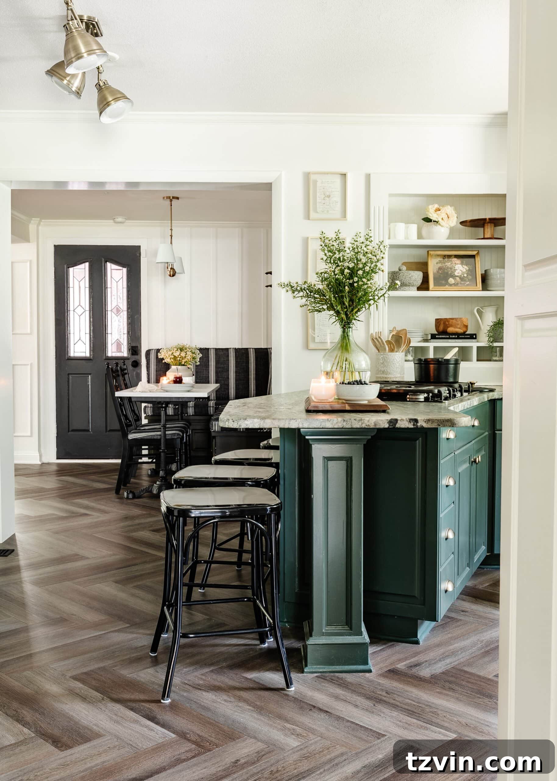 A charming cottagecore kitchen featuring white and green cabinets, elegant herringbone wood floors, a stylish brass faucet, a statement brass pendant light, and warm brass hardware, creating a serene and inviting atmosphere.