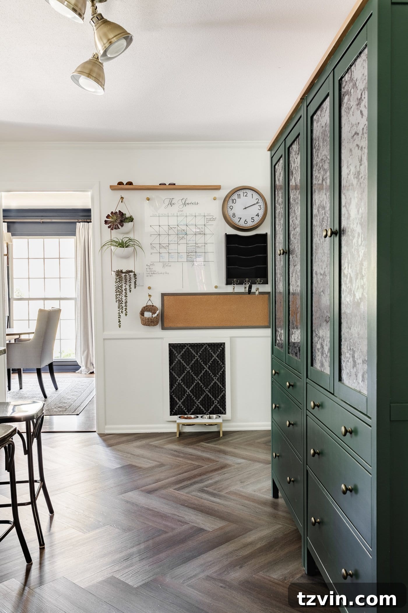 A well-organized family command center, complete with a calendar, memo board, and a convenient mail drop zone, perfectly integrated beside stylish IKEA pantry cabinets, enhancing daily efficiency.