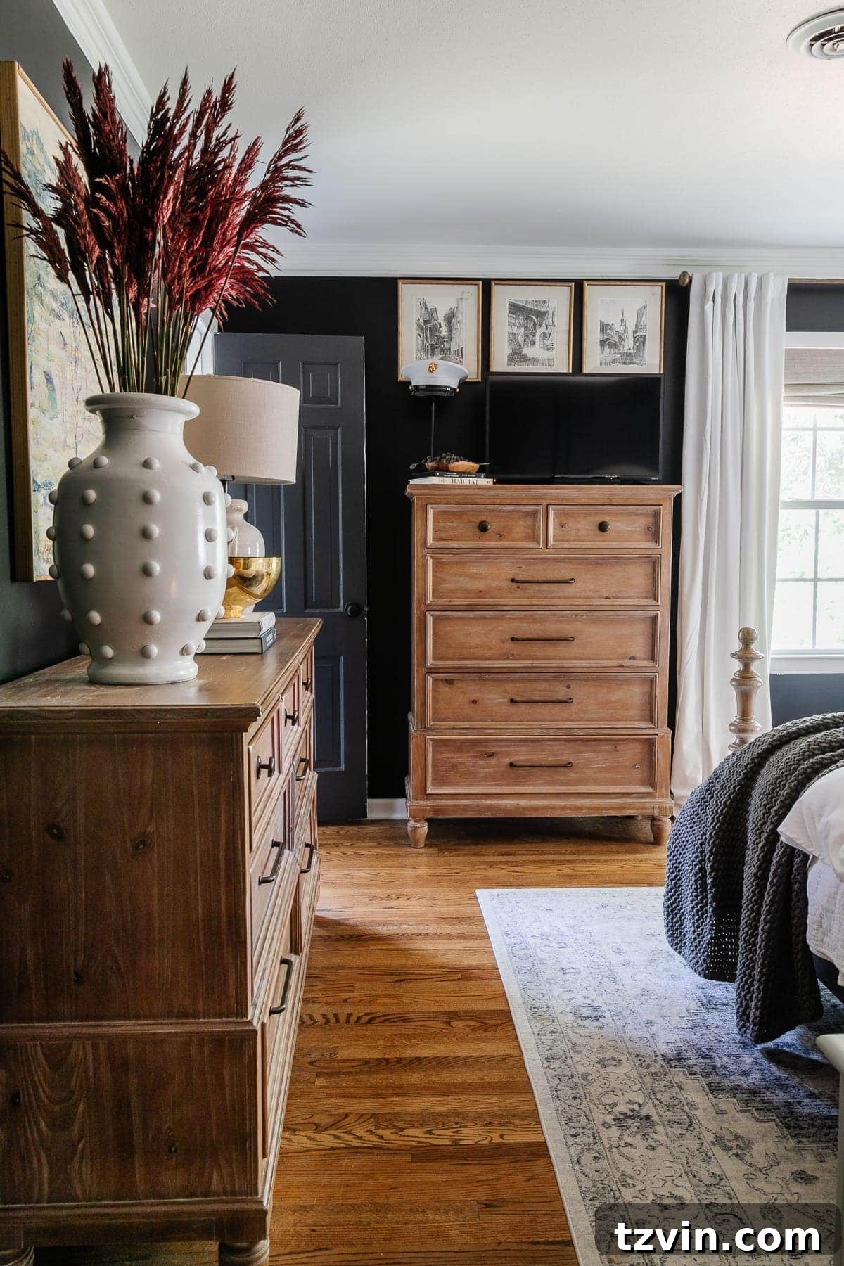 A luxurious black bedroom featuring elegant white curtains, sophisticated mirrored closet doors, a modern ceiling fan, and a plush upholstered wood bed, creating a serene and stylish retreat.