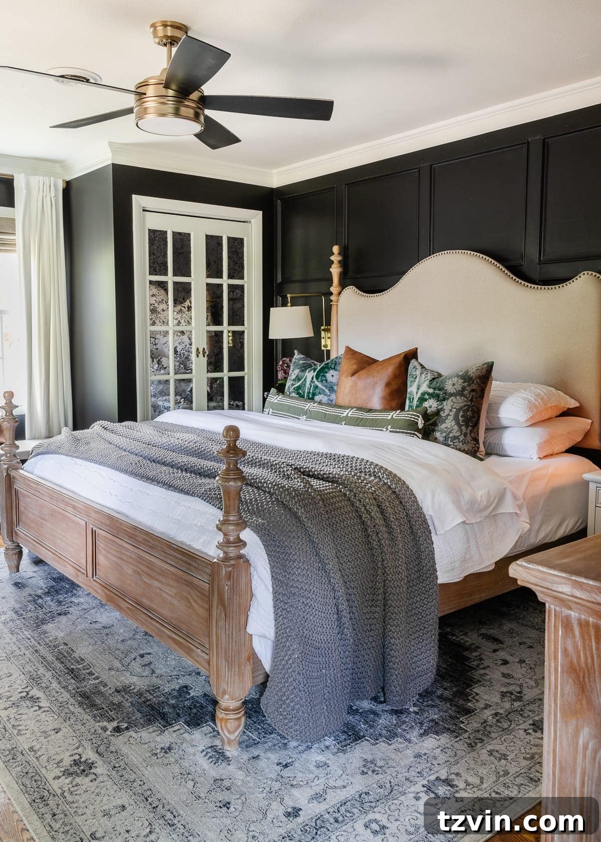 A luxurious black bedroom featuring elegant white curtains, sophisticated mirrored closet doors, a modern ceiling fan, and a plush upholstered wood bed, creating a serene and stylish retreat.