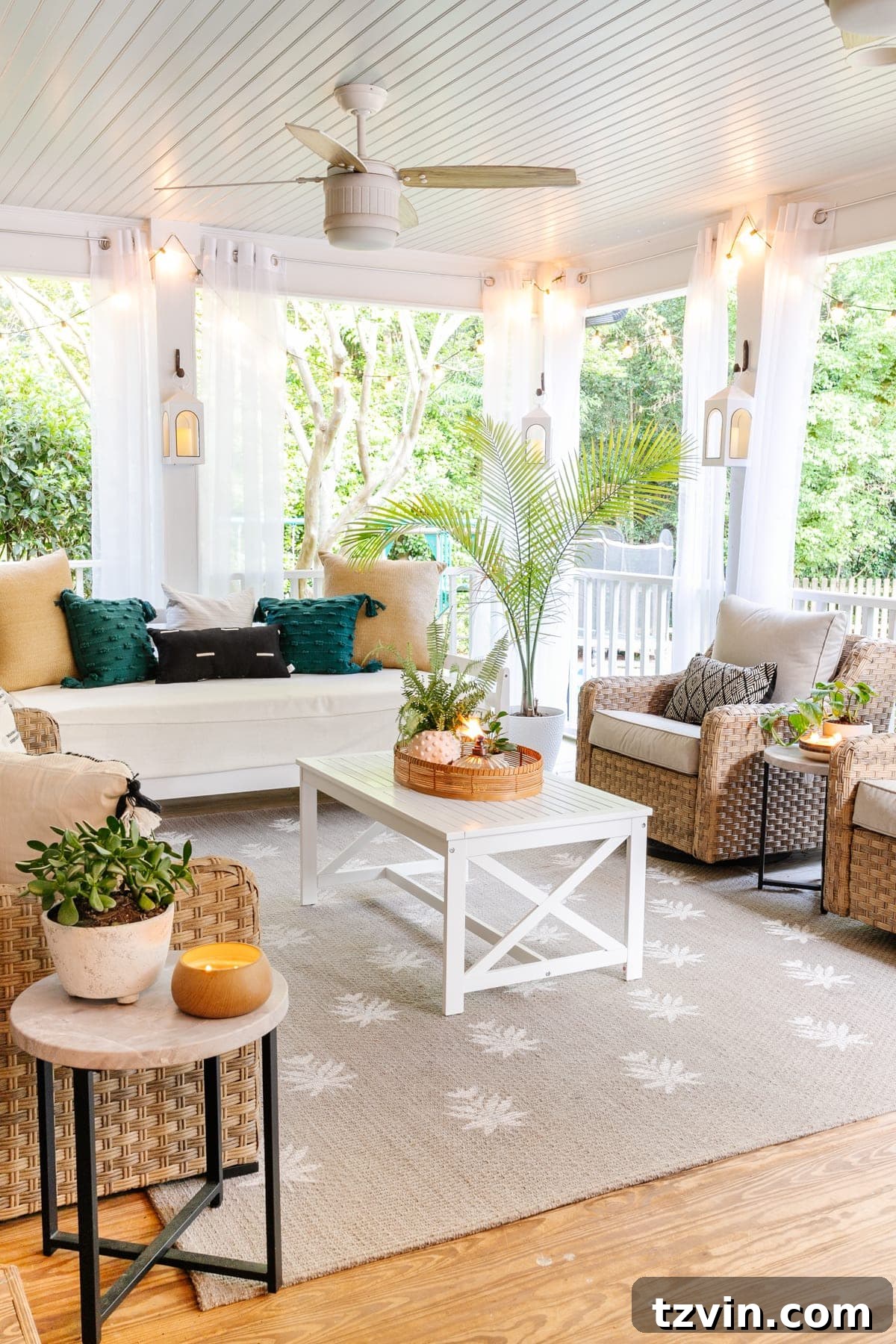 A beautifully transformed back porch featuring ethereal mosquito net curtains, twinkling string lights, a comfortable outdoor daybed, a stylish outdoor conversation set, and a vibrant floral block outdoor rug, creating a cozy and inviting outdoor living space.