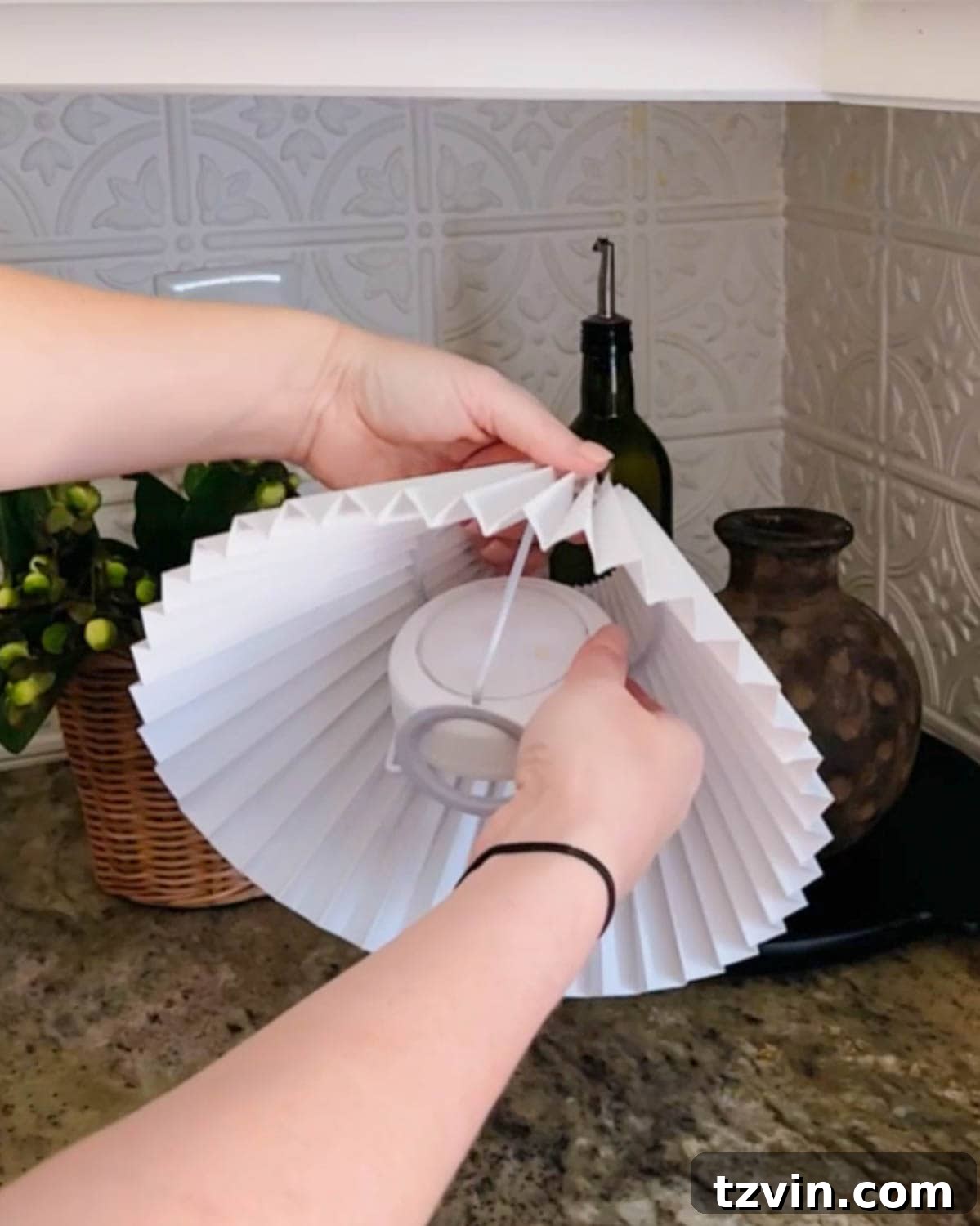 Demonstration of placing a battery-powered puck light securely inside a lamp shade's frame, preparing it for the vase base.