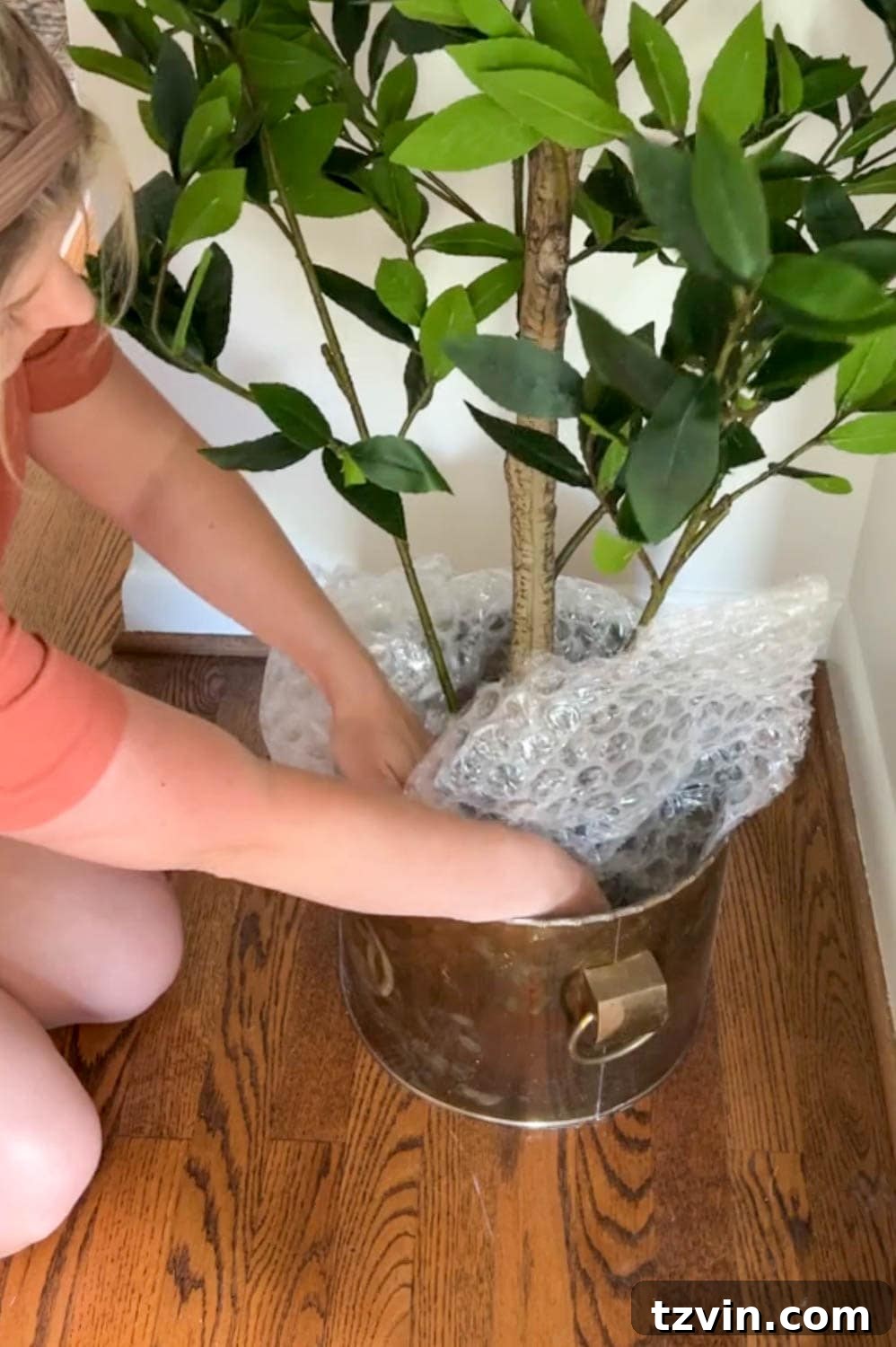 The Art of Creating Realistic Faux Trees 5 Stuffing a thrifted brass planter with bubble wrap and packing paper at the base of an artificial tree to create a hidden foundation