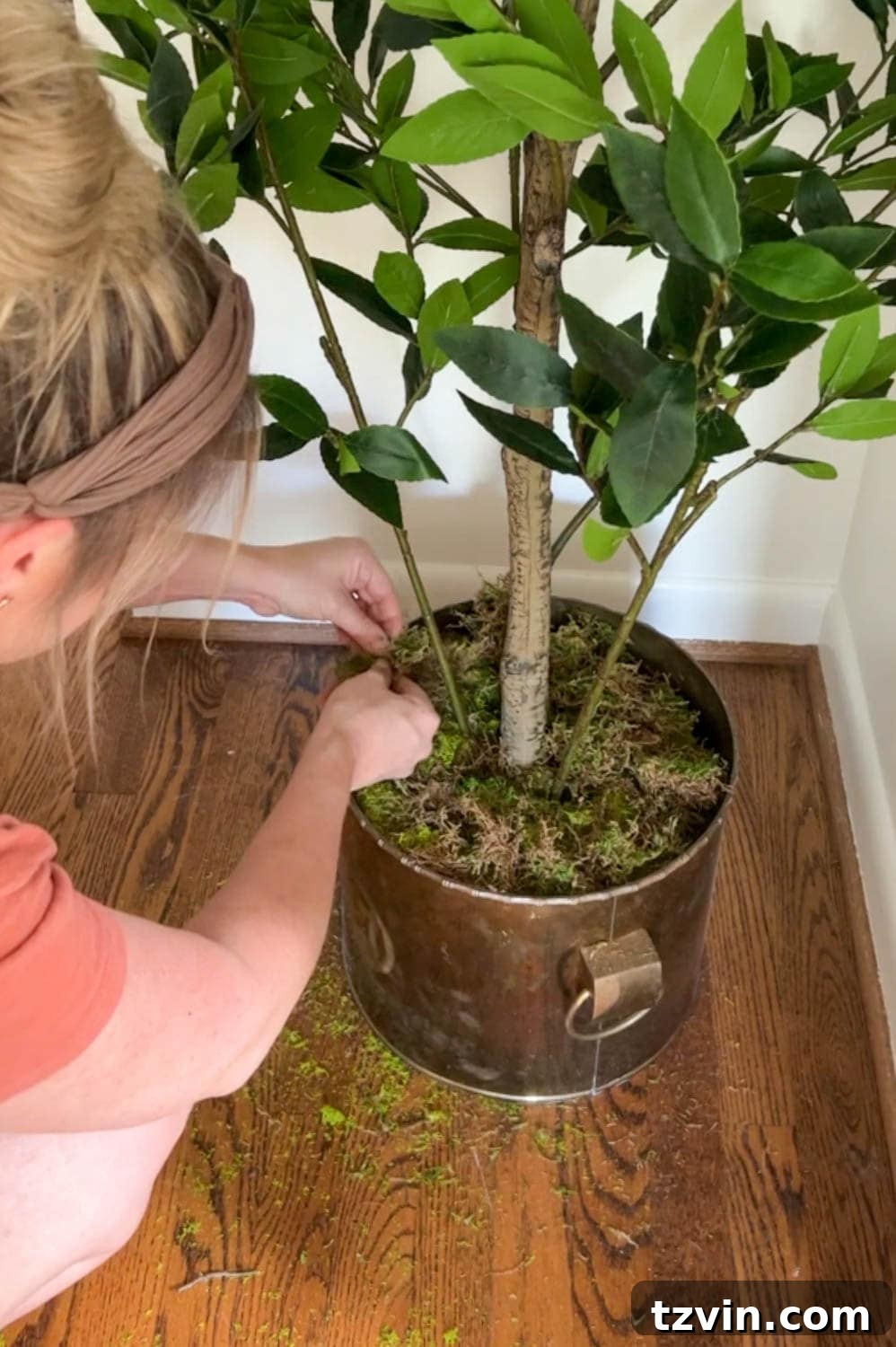 The Art of Creating Realistic Faux Trees 6 Adding green craft moss to a planter at the base of a faux tree, creating a realistic and natural top layer