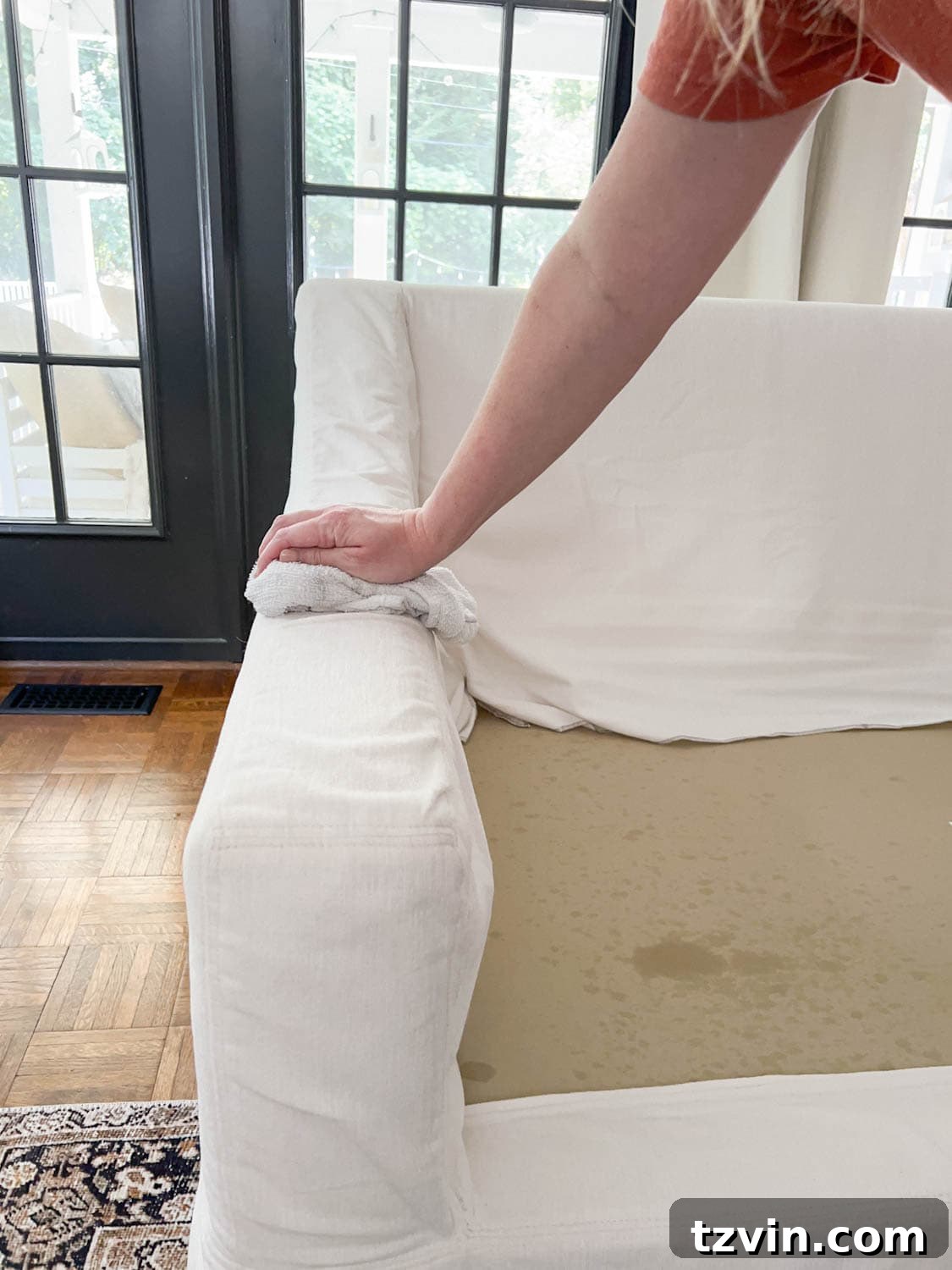 Wiping up DIY couch cleaner from upholstery to clean a sofa using a clean cloth.