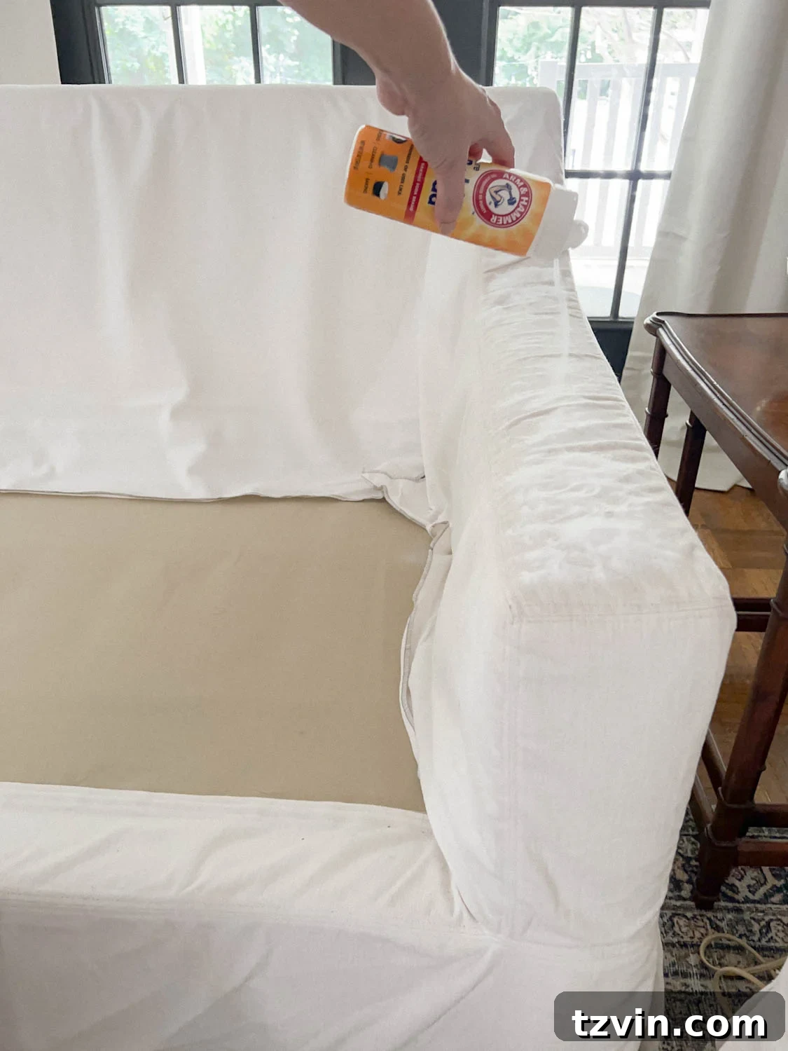 Baking soda generously sprinkled on the surface of a couch to deodorize and absorb odors.
