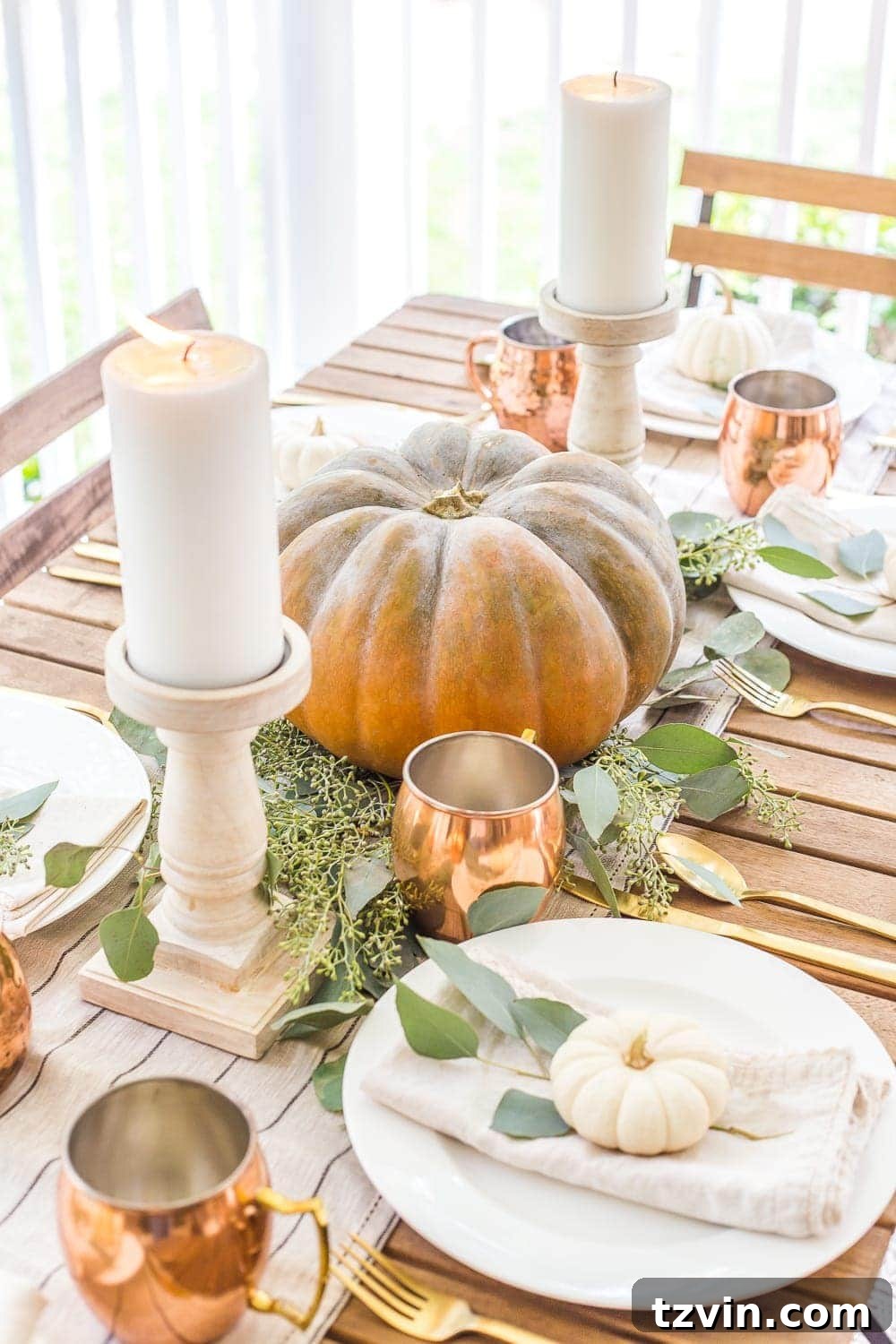 DIY fall centerpiece of simple pumpkin with eucalyptus leaves and pillar candles