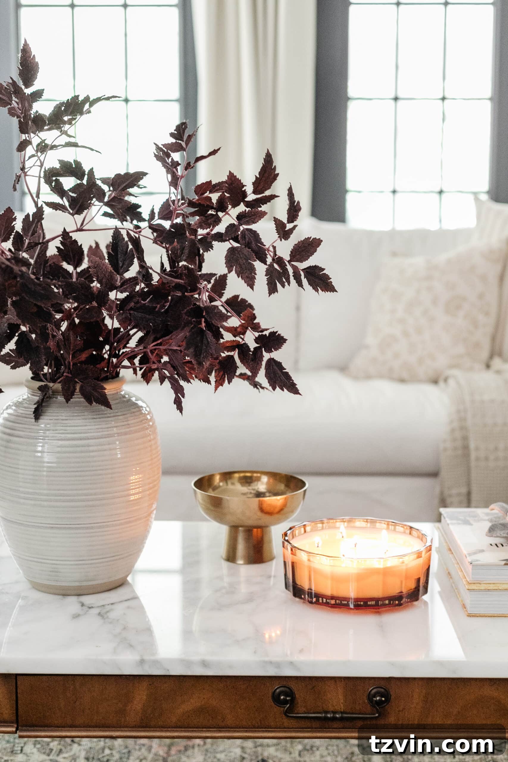Effortless Autumn Living Room Decor for Less 14 Fall decor on a coffee table with vase of fall branches, candle, brass bowl, and books