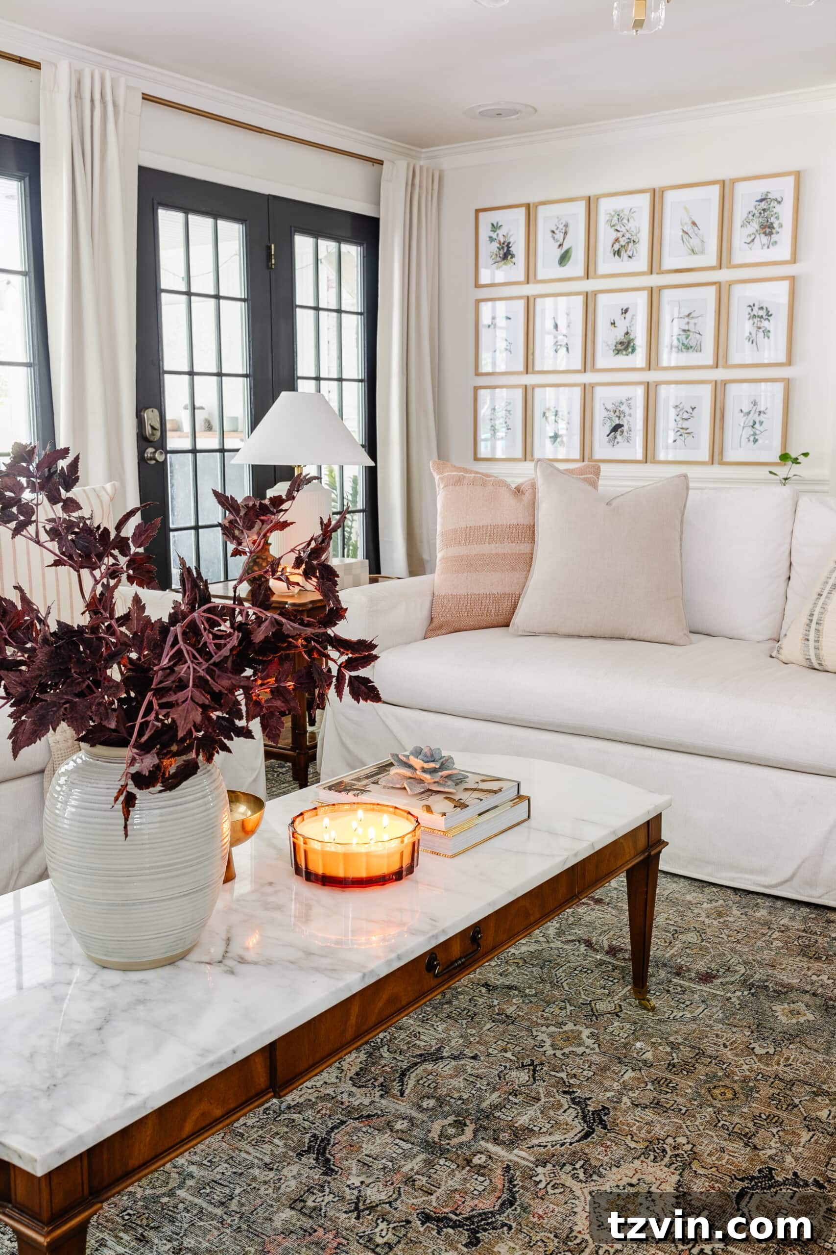 Effortless Autumn Living Room Decor for Less 21 Coffee table fall decor with vase of fall stems, candle, bowl, and books in front of white sofa with neutral pillows