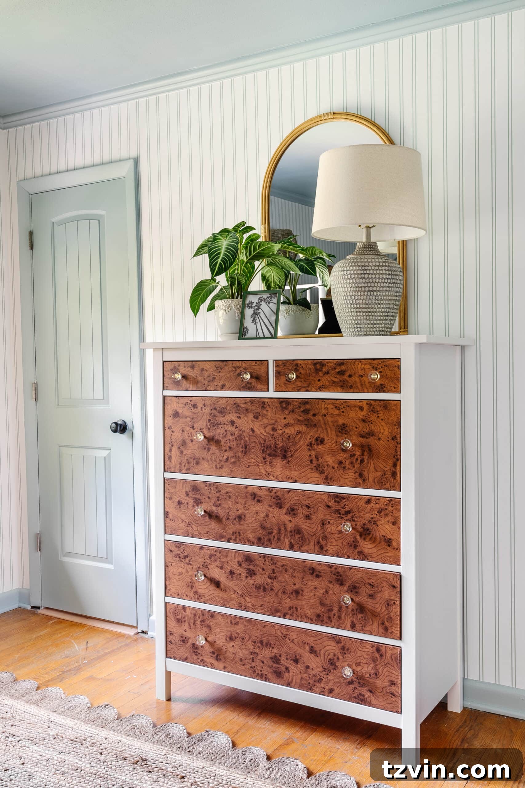 IKEA dresser hack using burl wood contact paper, striped wallpaper, blue trim, rattan mirror, and coastal table lamp