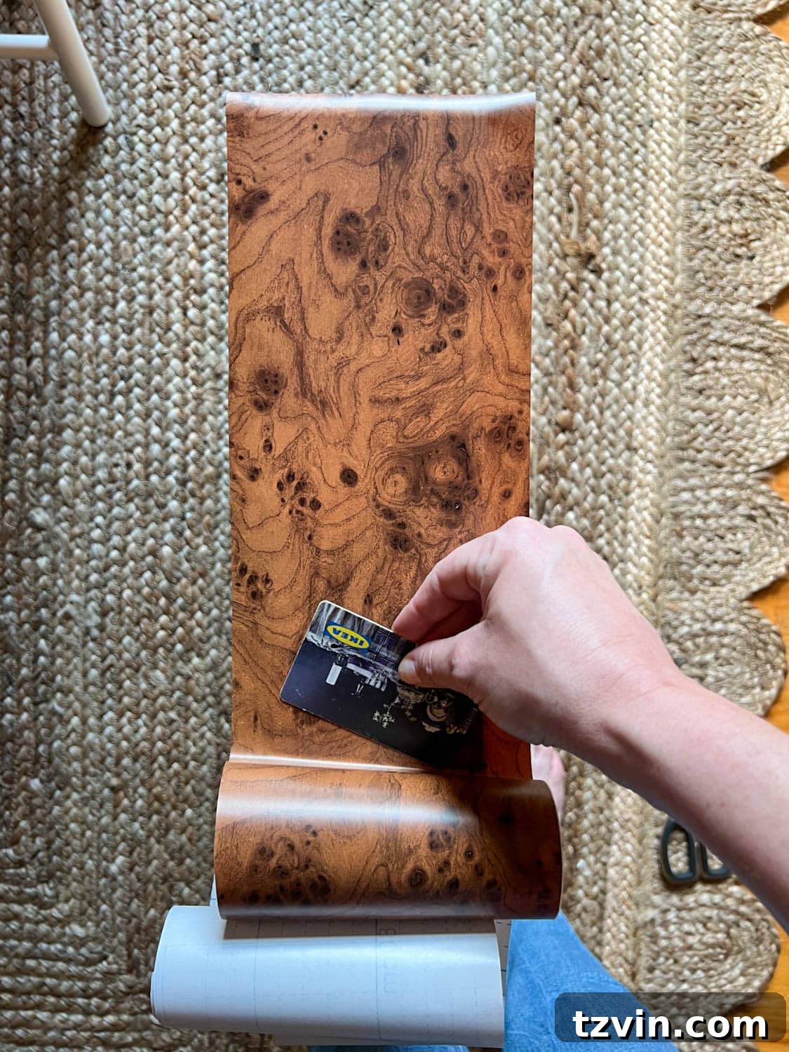 smoothing out burl wood contact paper to dresser drawer front