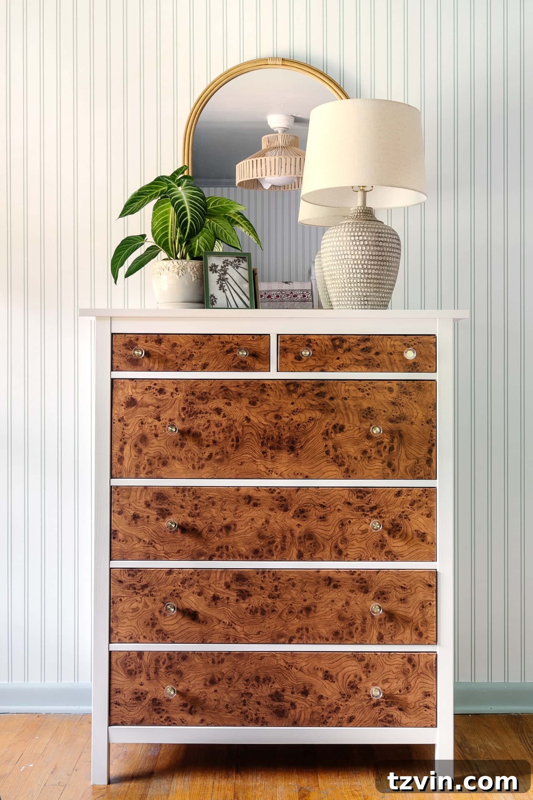 IKEA hack burl wood dresser with contact paper, arched rattan mirror, and coastal lamp
