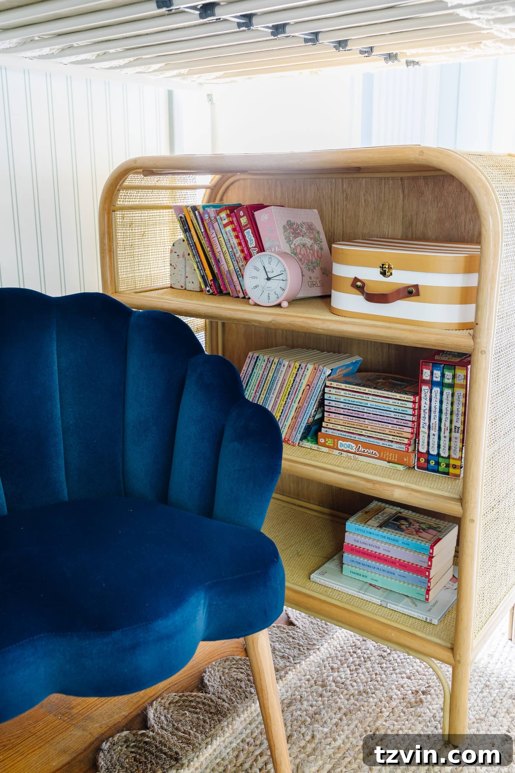 Cozy kids' reading nook with scalloped chairs and a rattan bookshelf under a loft bunk