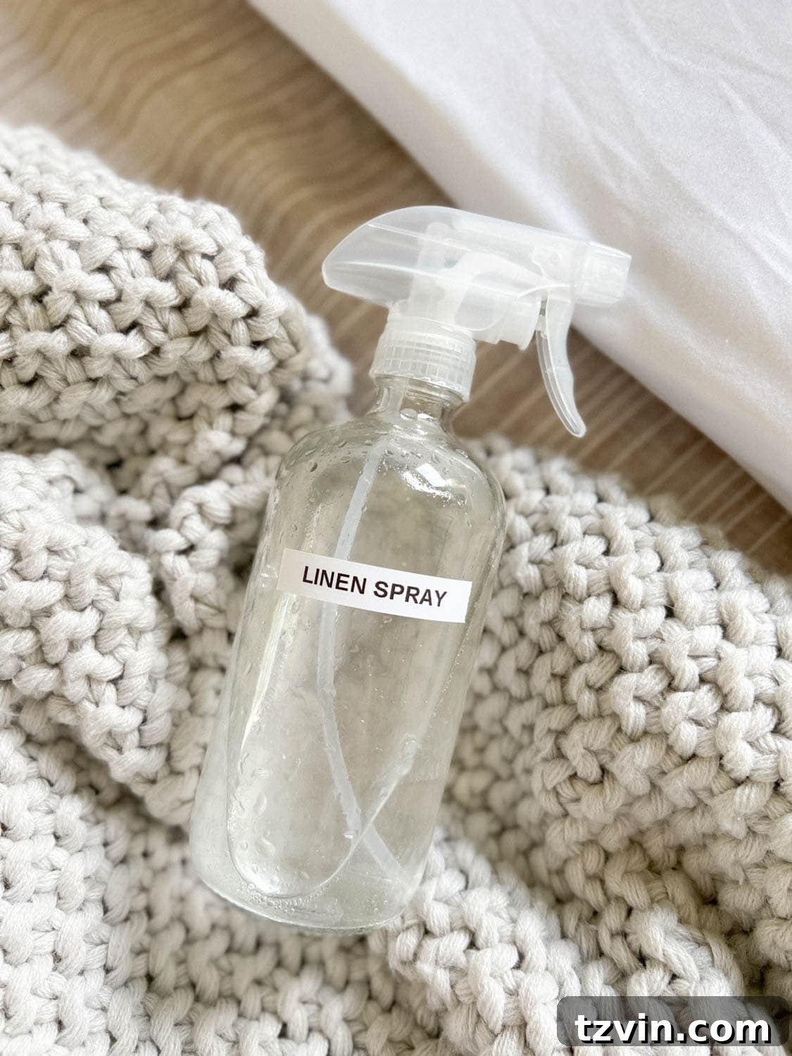 DIY linen spray in a glass spray bottle on bedding