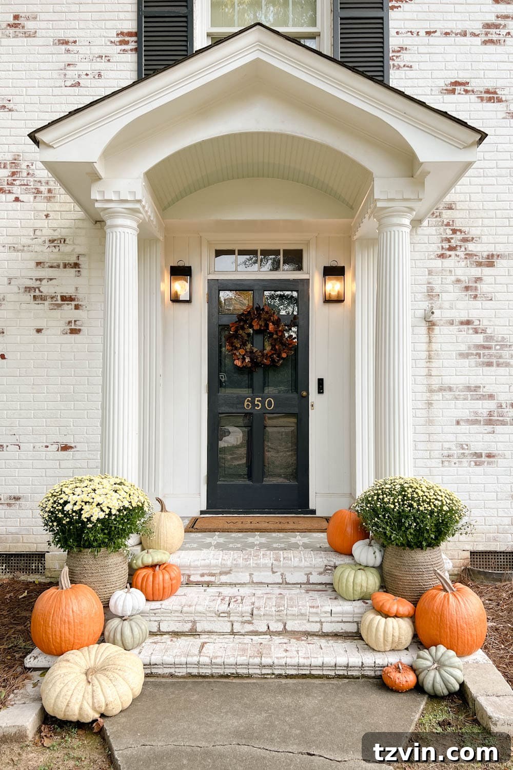 Harvesting Realism: The Top Fake Pumpkins of 2024 6 A welcoming fall front porch featuring potted mums, a festive wreath, and a collection of realistic fake pumpkins artfully arranged on the steps, creating a cozy autumn display.