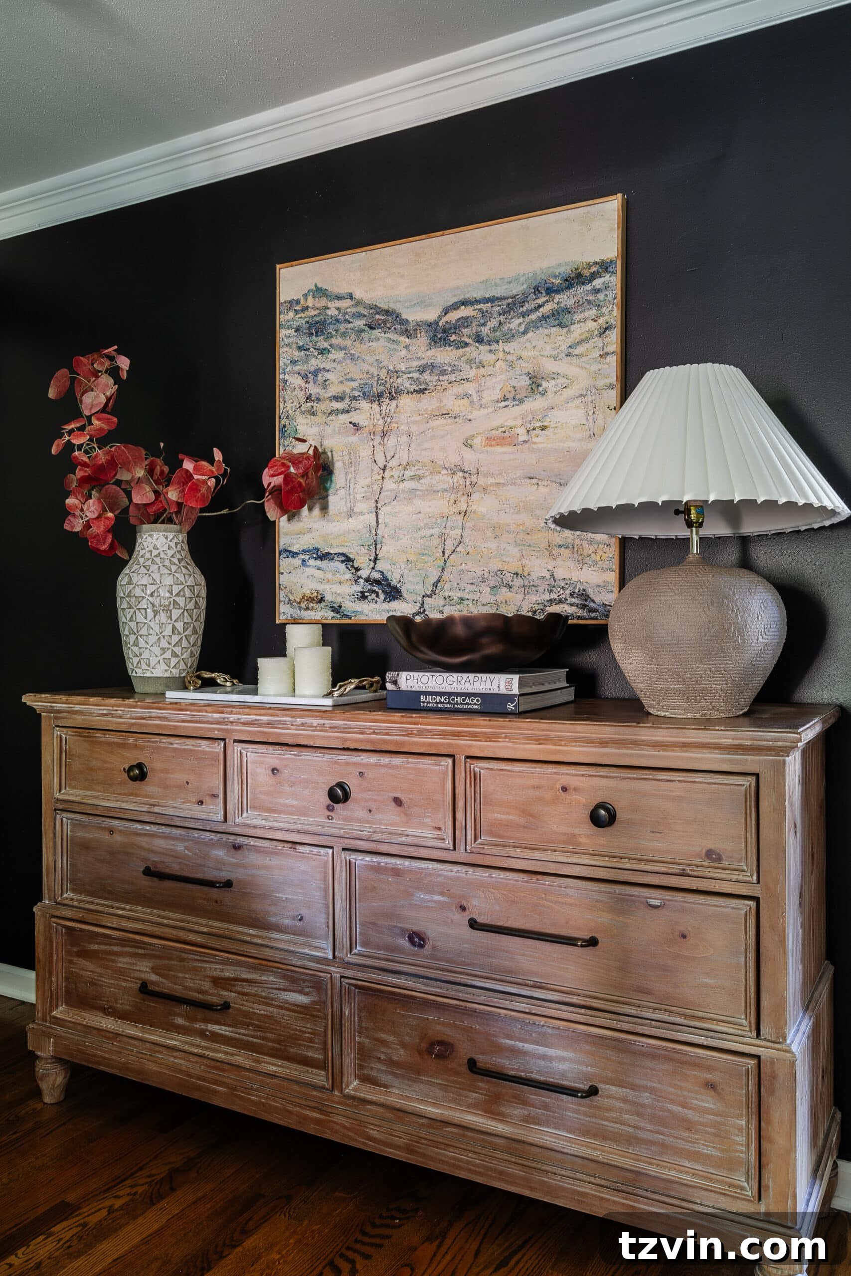 10 Budget-Friendly Ways to Create a Cozy Sleep Haven 4 wood dresser with large wall art, vase of fall branches, and table lamp