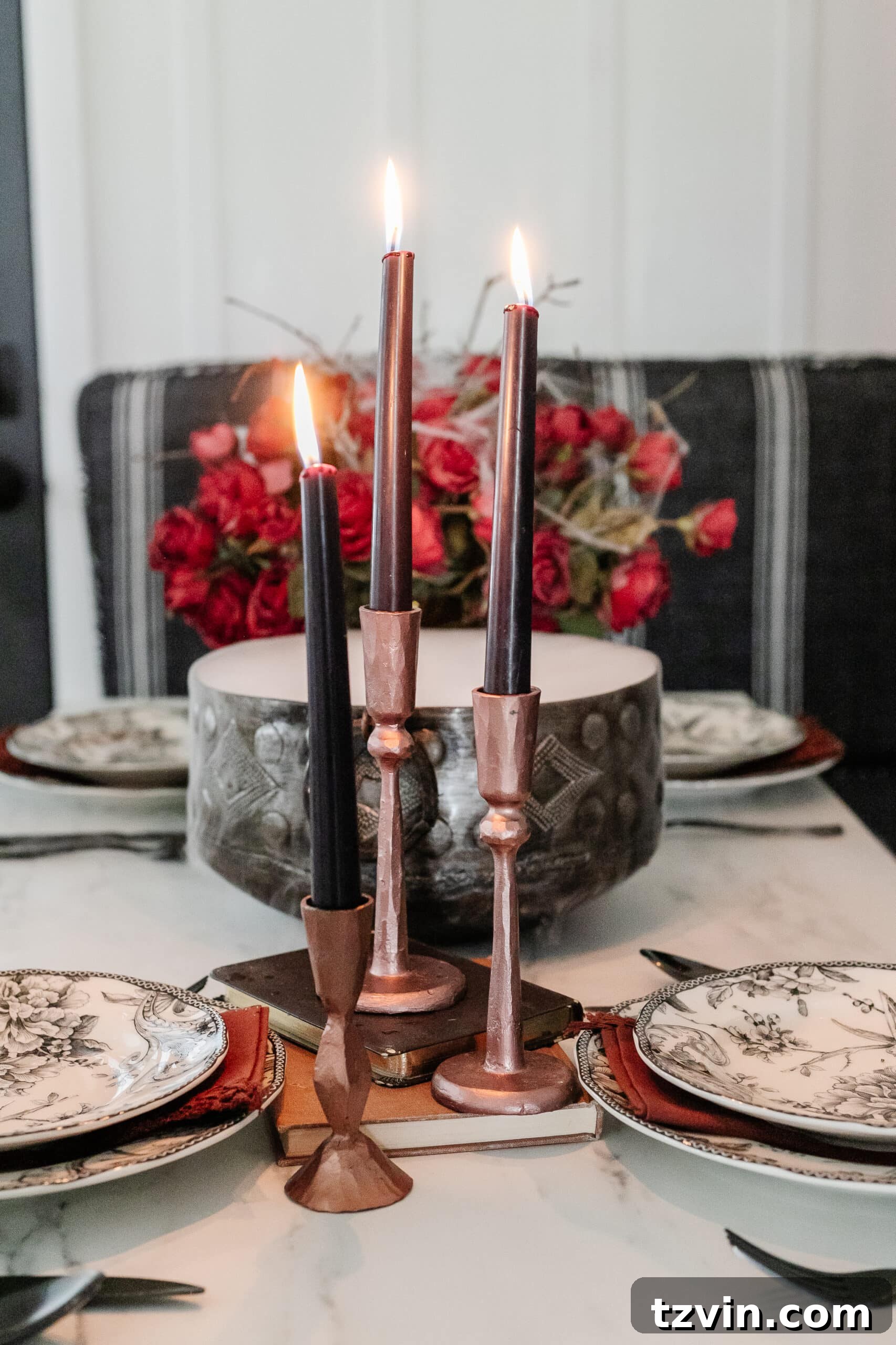 Killer Tablescapes: Spooky Settings for Your Murder Mystery Party 12 Hammered copper candlesticks with elegant black candles, artfully stacked on old books for a vintage-inspired display