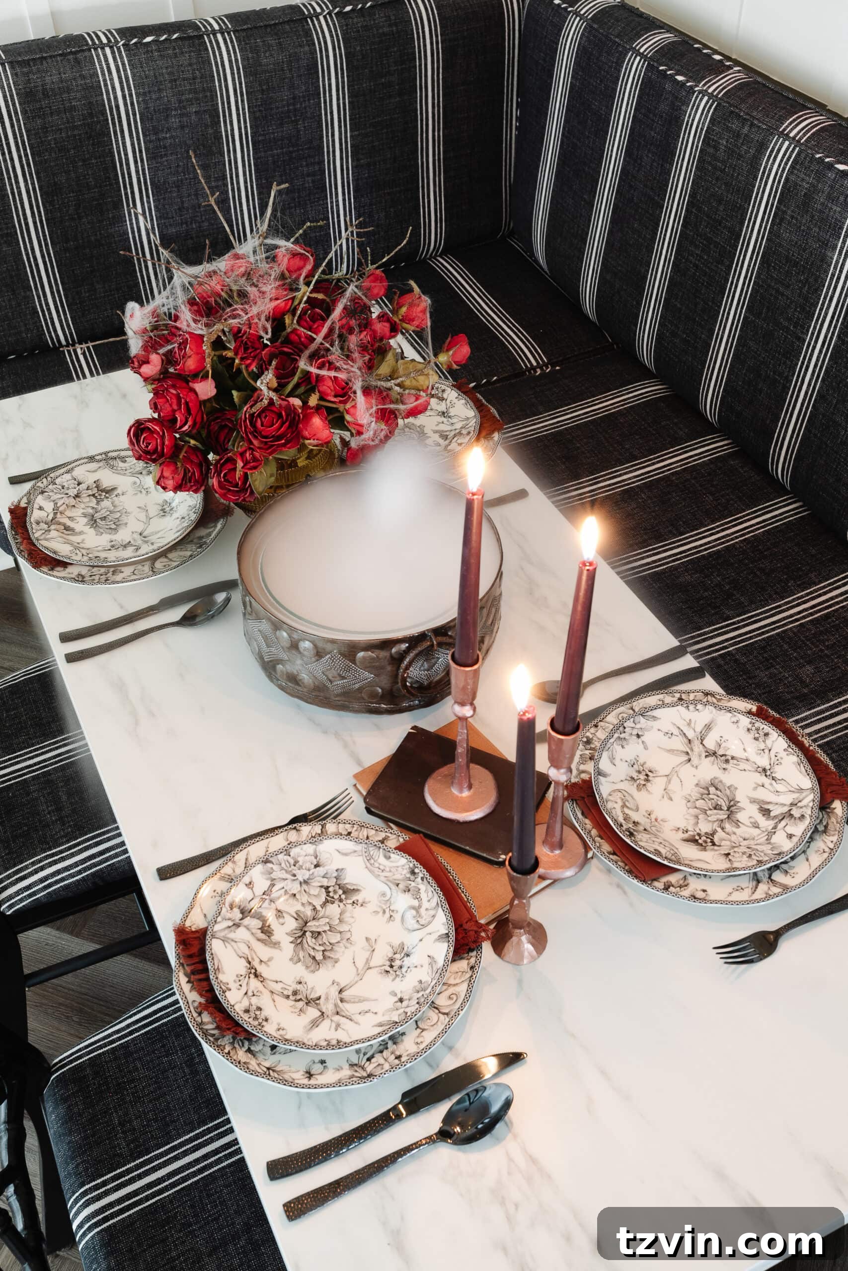 Killer Tablescapes: Spooky Settings for Your Murder Mystery Party 4 Murder mystery party table decor featuring black toile dinnerware, a cauldron with dry ice fog, and red roses adorned with spider webs