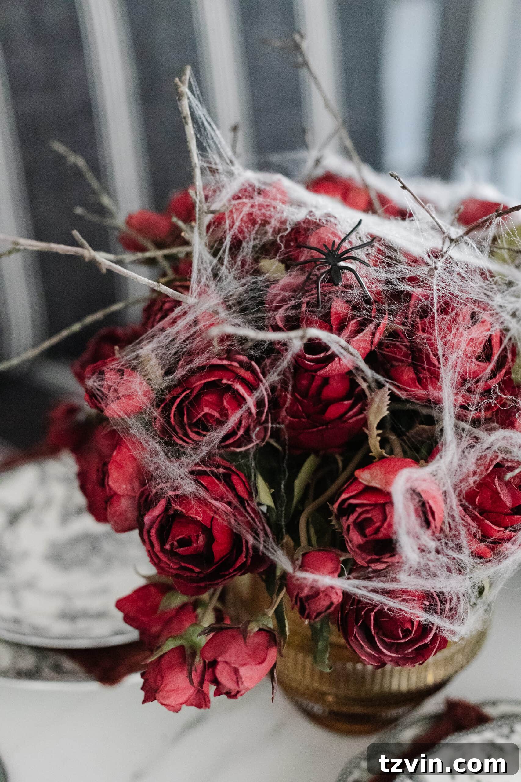 Killer Tablescapes: Spooky Settings for Your Murder Mystery Party 7 Vase of red roses with delicate spider webs, forming a simple yet elegant Halloween flower arrangement