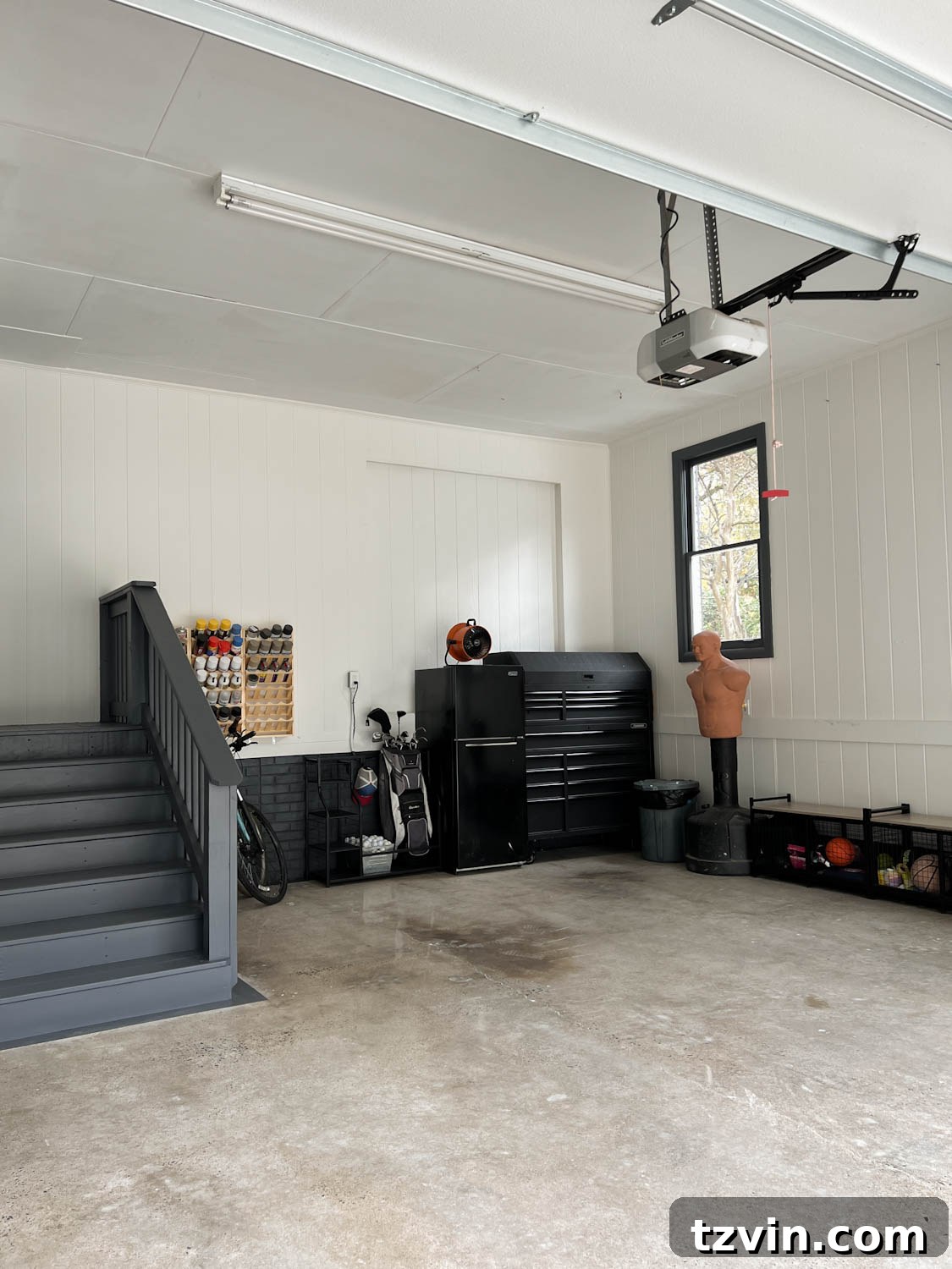 A garage after makeover, showing organized tools in a chest, repurposed paint, and a refinished concrete floor.