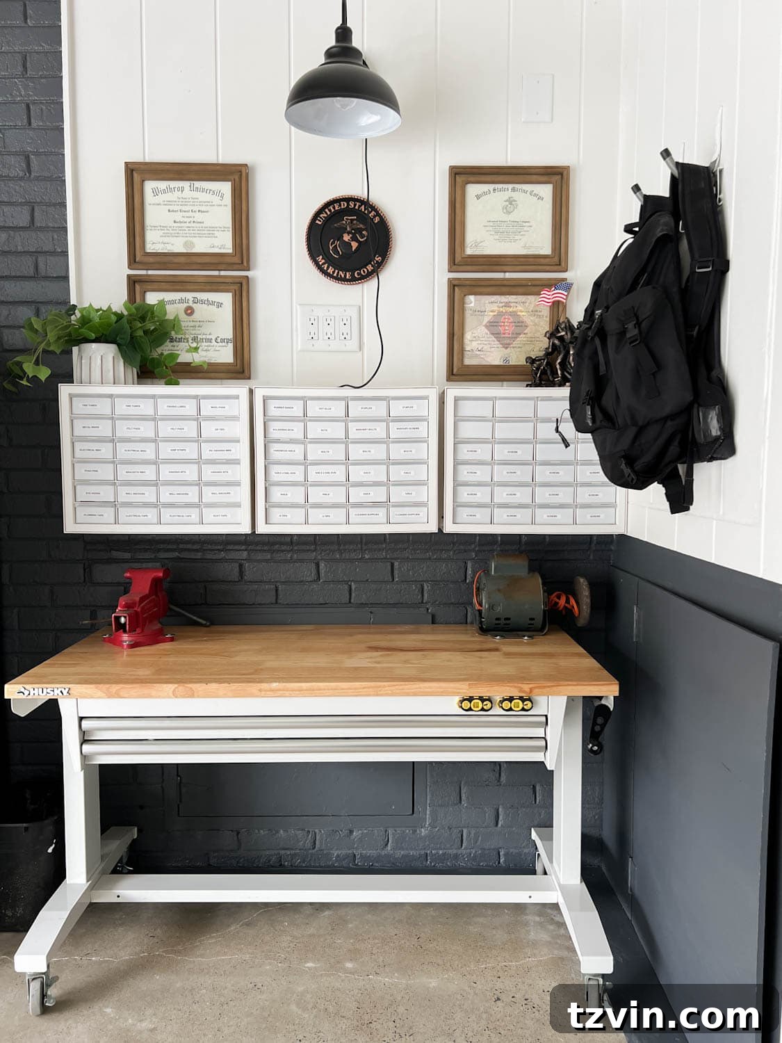 A rolling workbench positioned under hardware organizers in a garage workshop, providing both workspace and storage.
