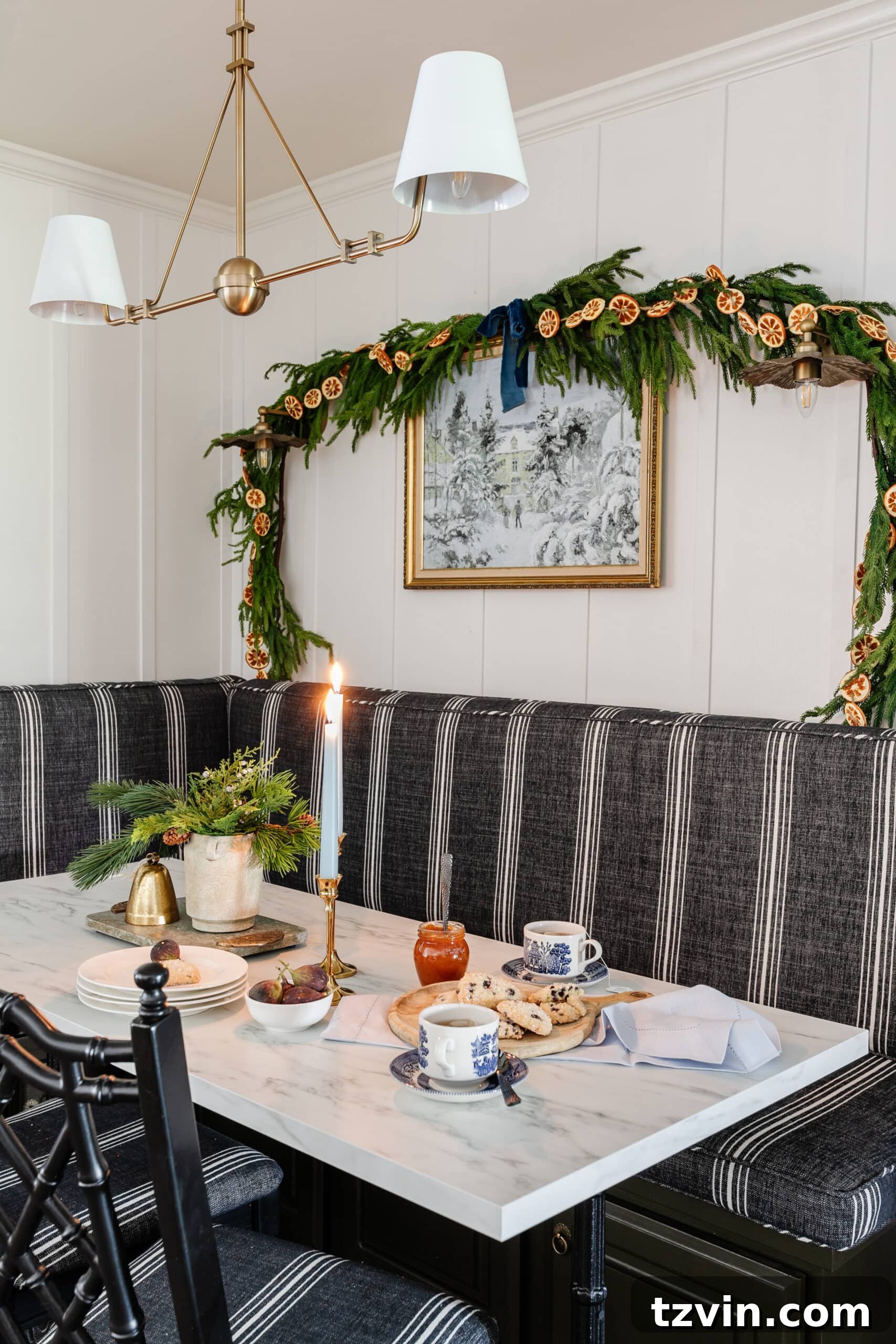 Instant Winter Art: Free Printable Decor 5 Enchanting winter scene painting adorning a breakfast nook wall, beautifully framed and accented with pine and orange garland.