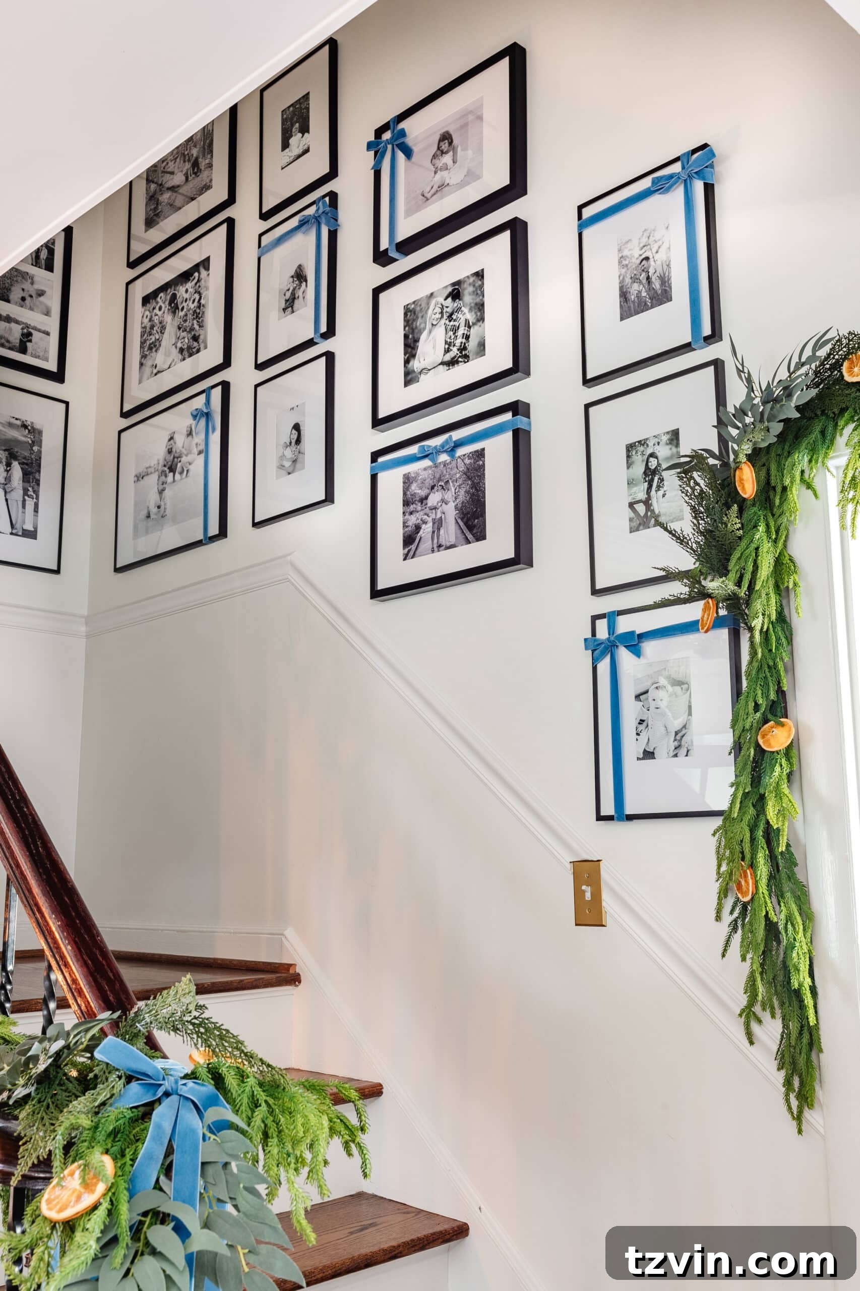 Effortless 5 Minute Holiday Ribbon Art 9 A beautifully decorated family photo gallery wall with blue Christmas bows on the frames, creating easy and elegant ribbon art for the holidays.