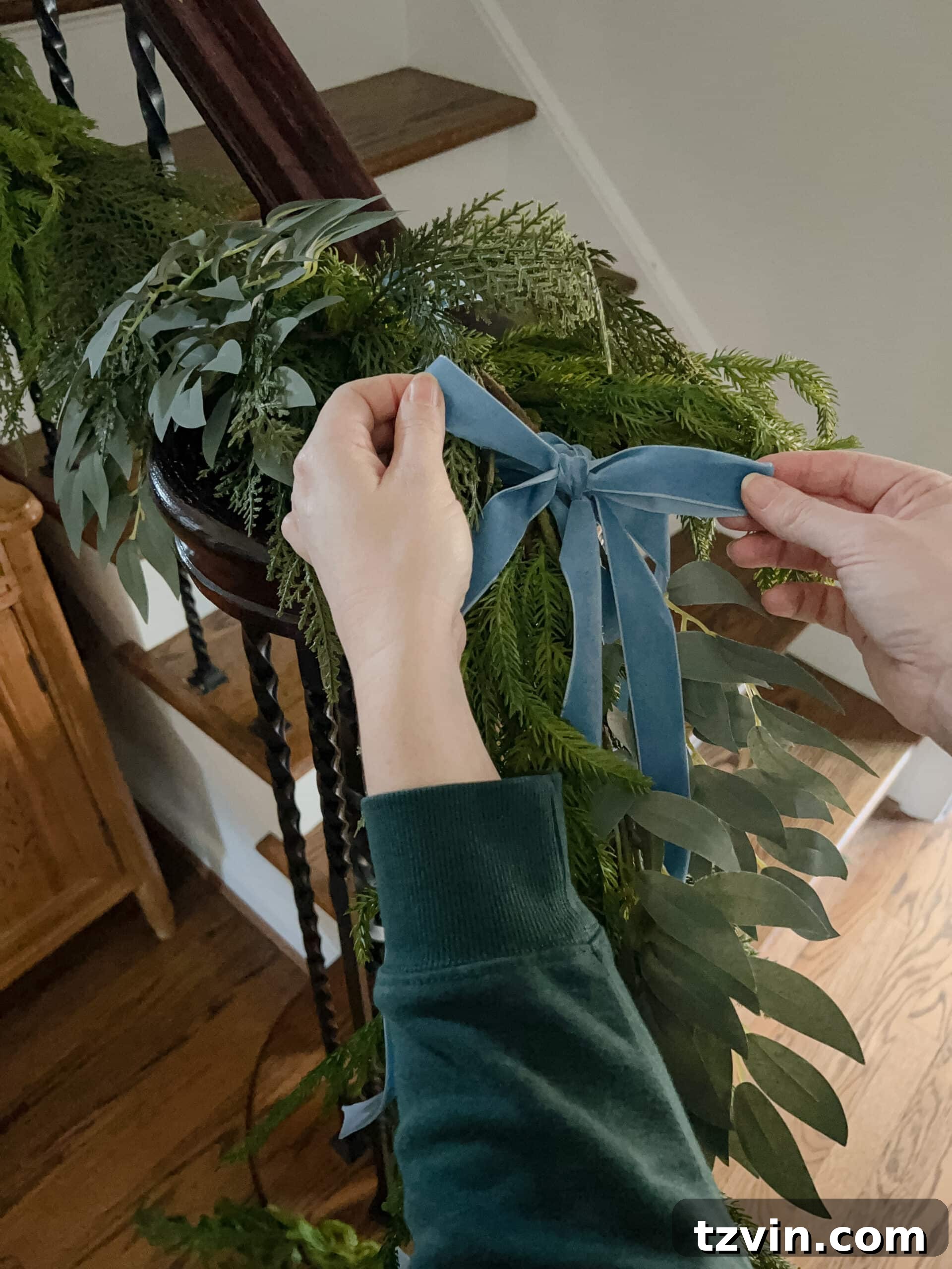 Sparkling Stairs and Welcoming Entryways: Your Garland Decor Guide 12 adding bows to staircase garland for a festive touch