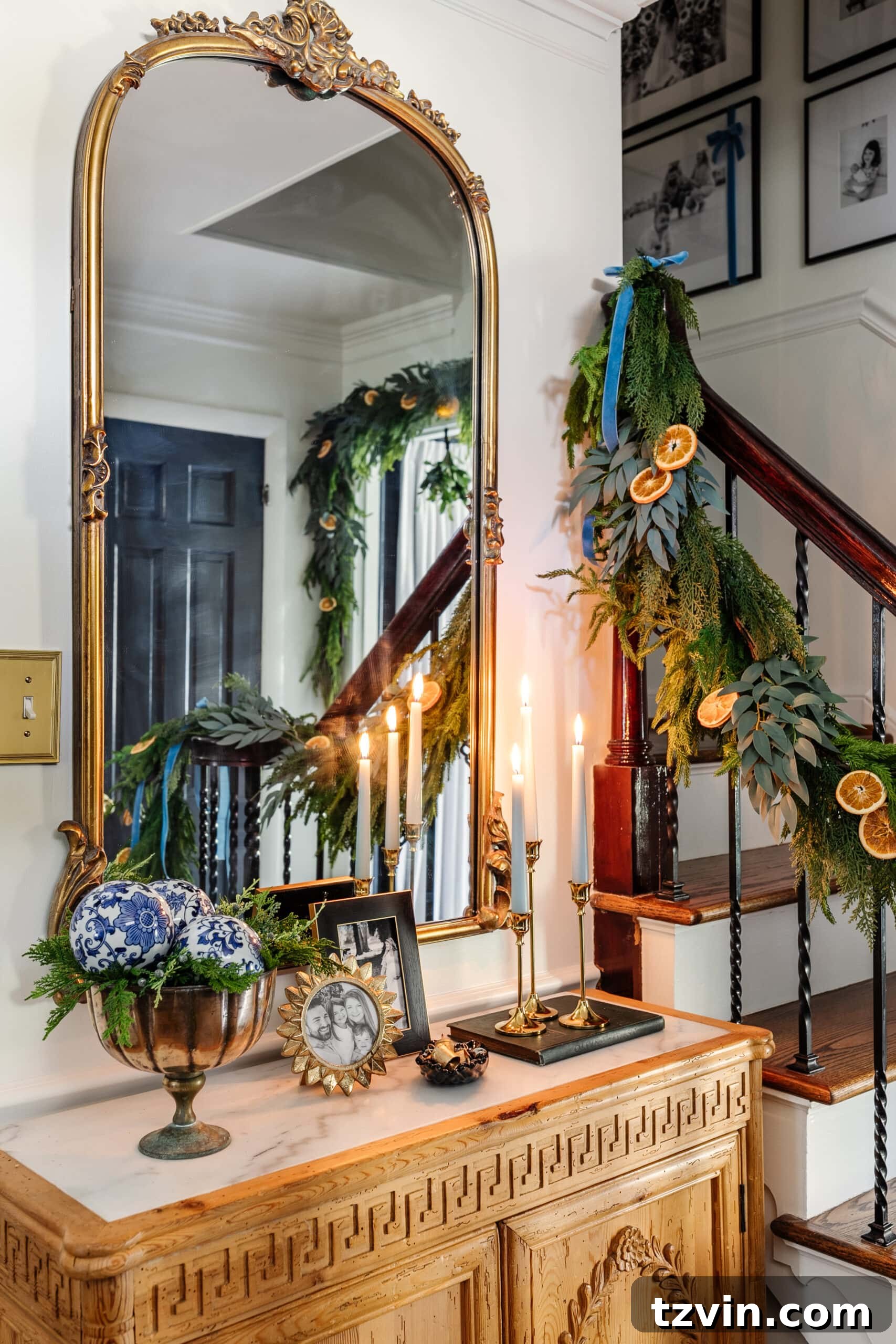 Sparkling Stairs and Welcoming Entryways: Your Garland Decor Guide 19 entryway Christmas decor on a table with candles, mirror, picture frames, and bowl of greenery