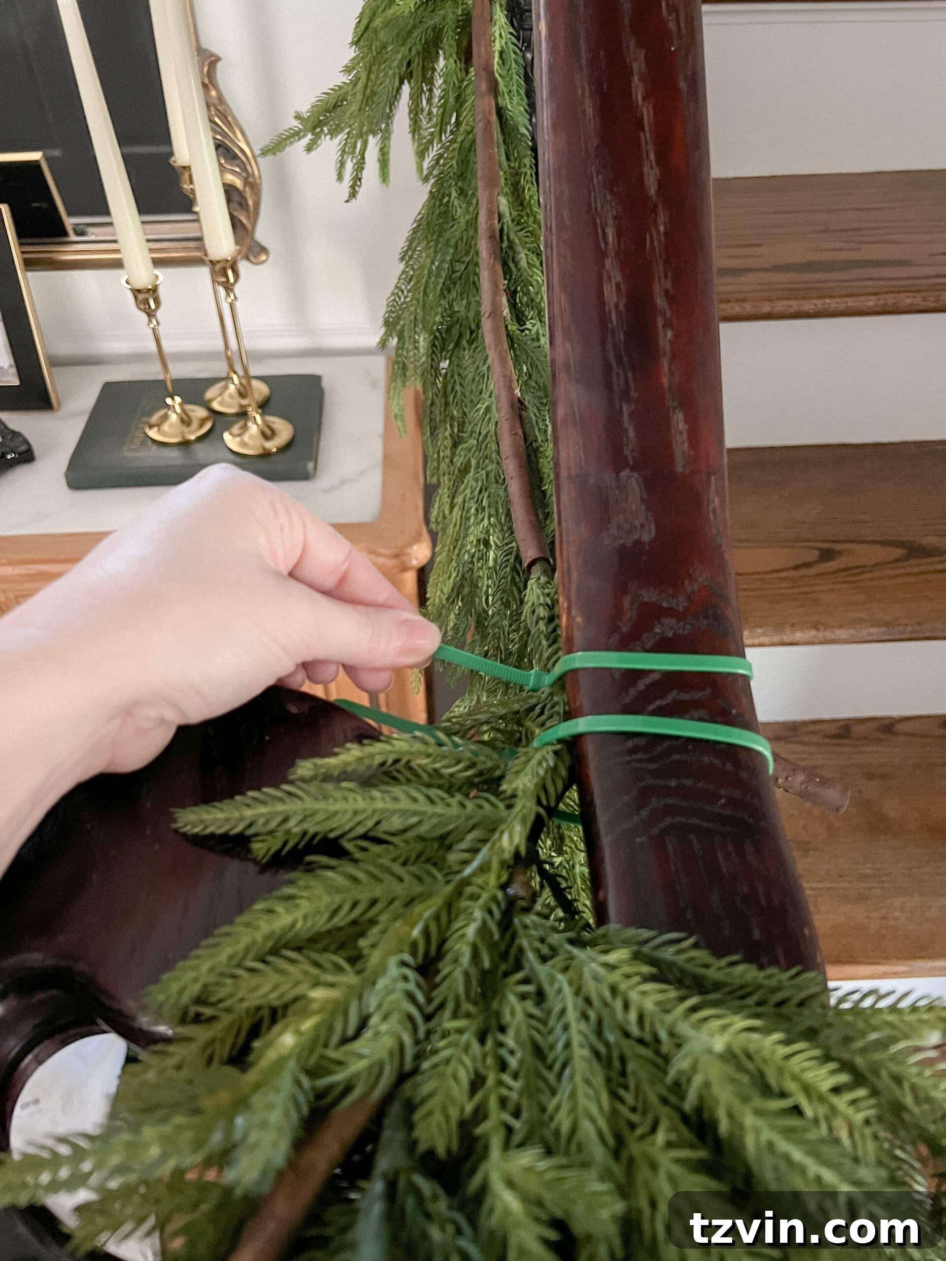 Sparkling Stairs and Welcoming Entryways: Your Garland Decor Guide 5 securing garland on stairs banister with zip ties