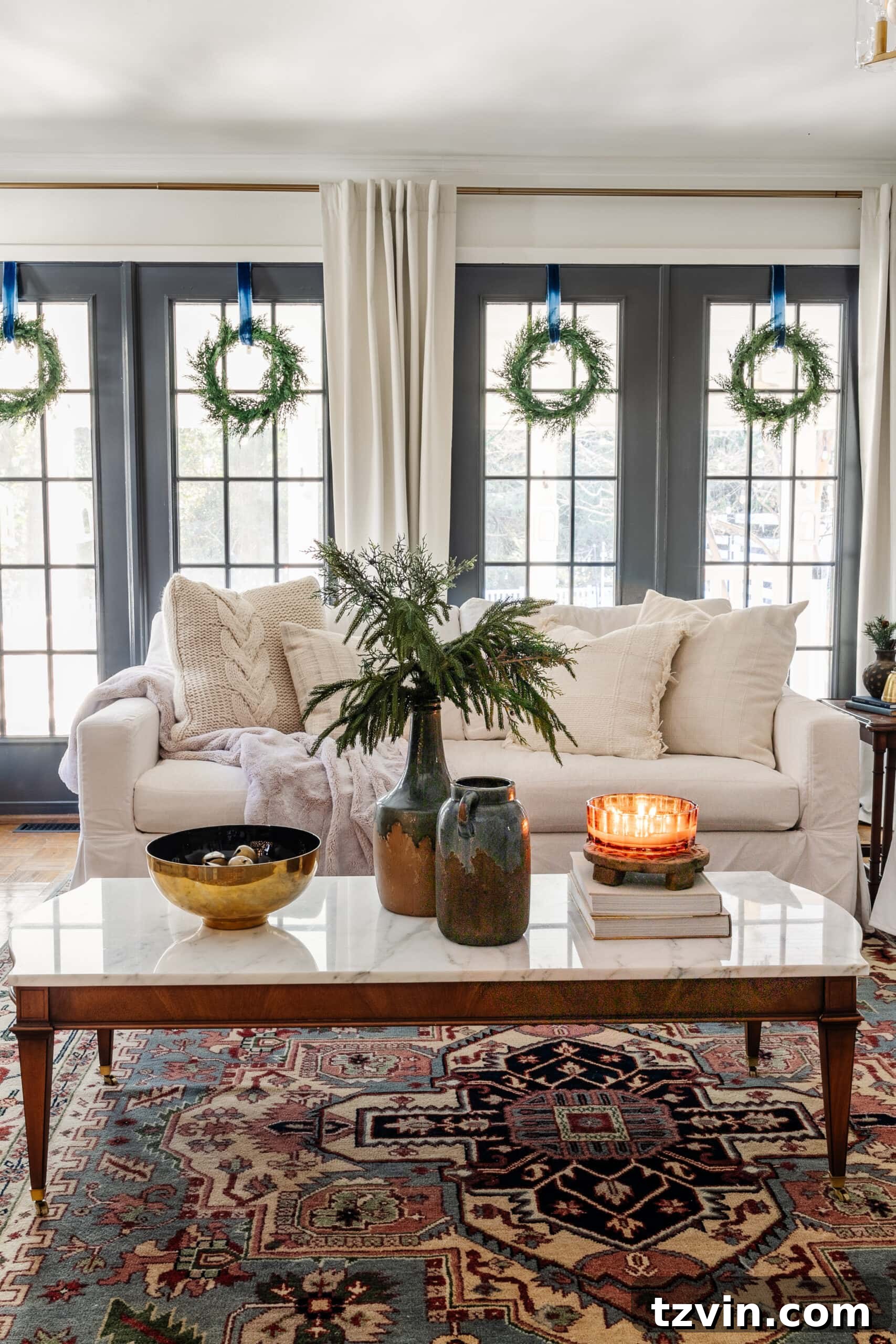 Snuggle-Worthy: 13 Christmas Living Room Decor Inspirations 10 marble top coffee table with Christmas greenery in vase, bowl of jingle bells, and candle