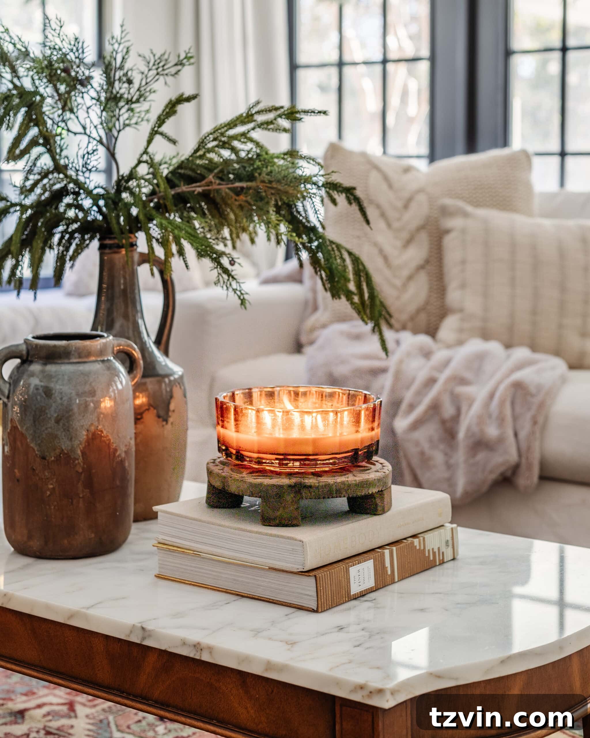 candle, books, and vase with winter branches on a coffee table for January decor 