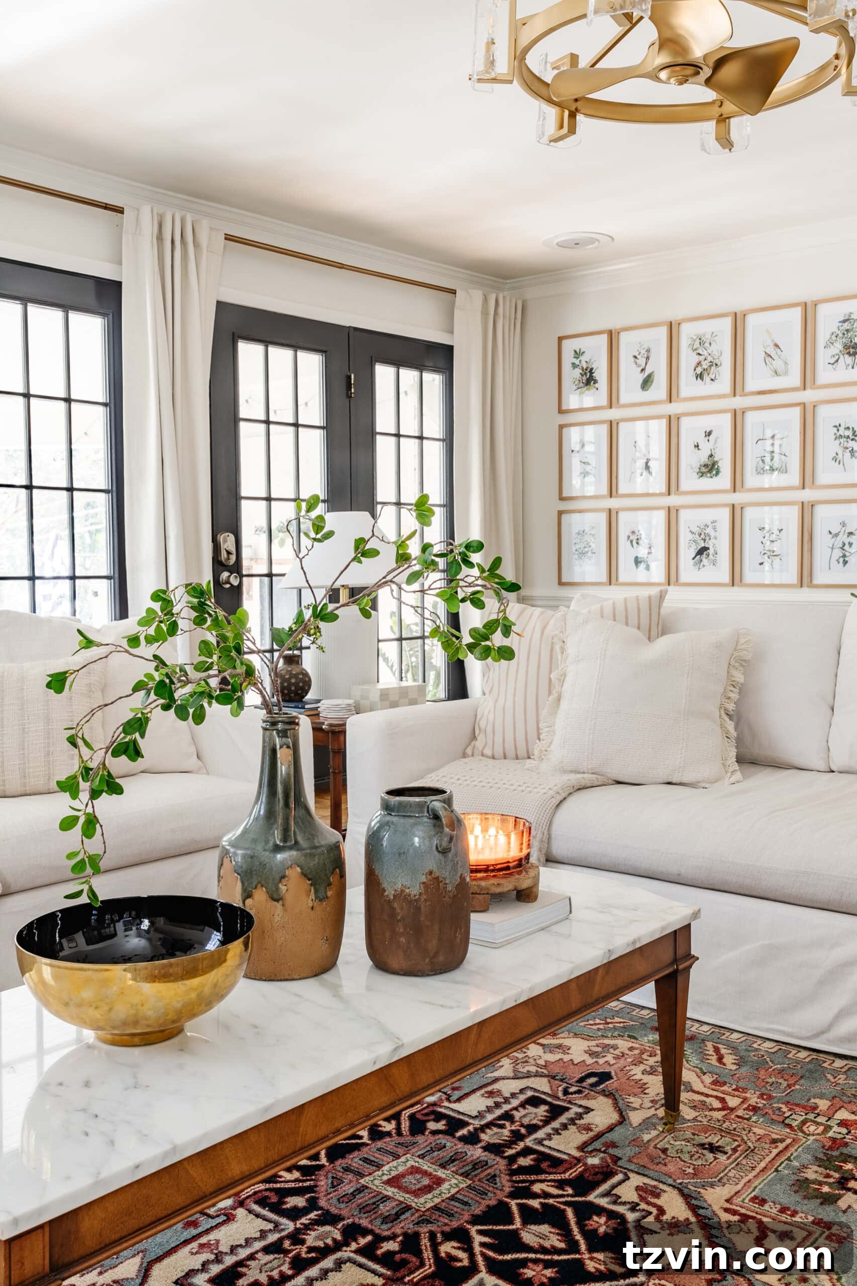 winter living room January decor with white sofas, candle, and vase of greenery on coffee table