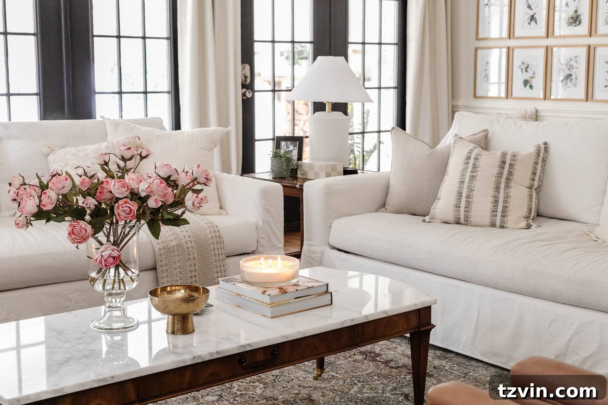 marble top coffee table in living room with couches and vase of pink roses