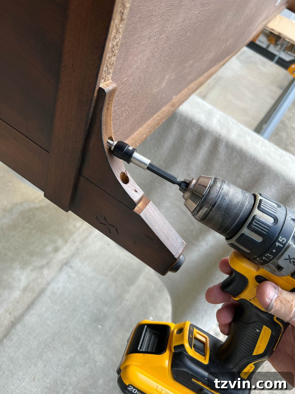 Reeded Elegance: A Shoe Storage Bench Makeover 6 Close-up view of a person removing furniture legs with a drill, preparing for replacement with new stylish legs