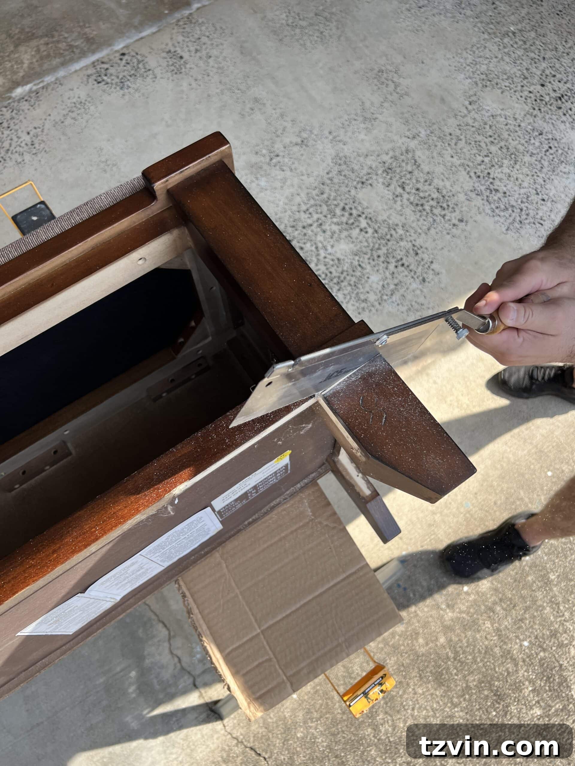 Reeded Elegance: A Shoe Storage Bench Makeover 7 Detailed shot of a hand saw being used to carefully cut off existing furniture legs in preparation for replacement