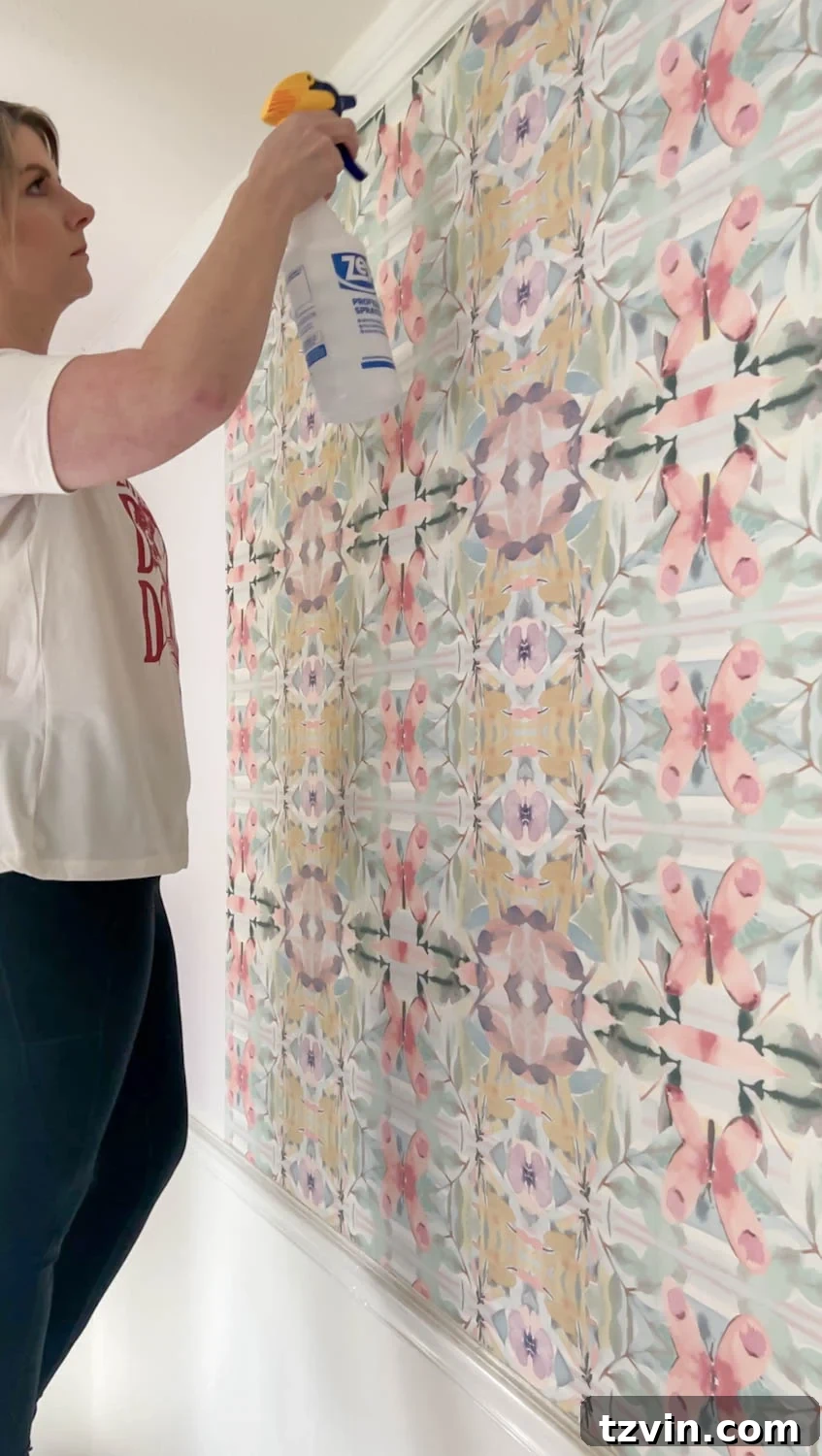 Spraying vinegar solution on wallpaper to aid in its removal