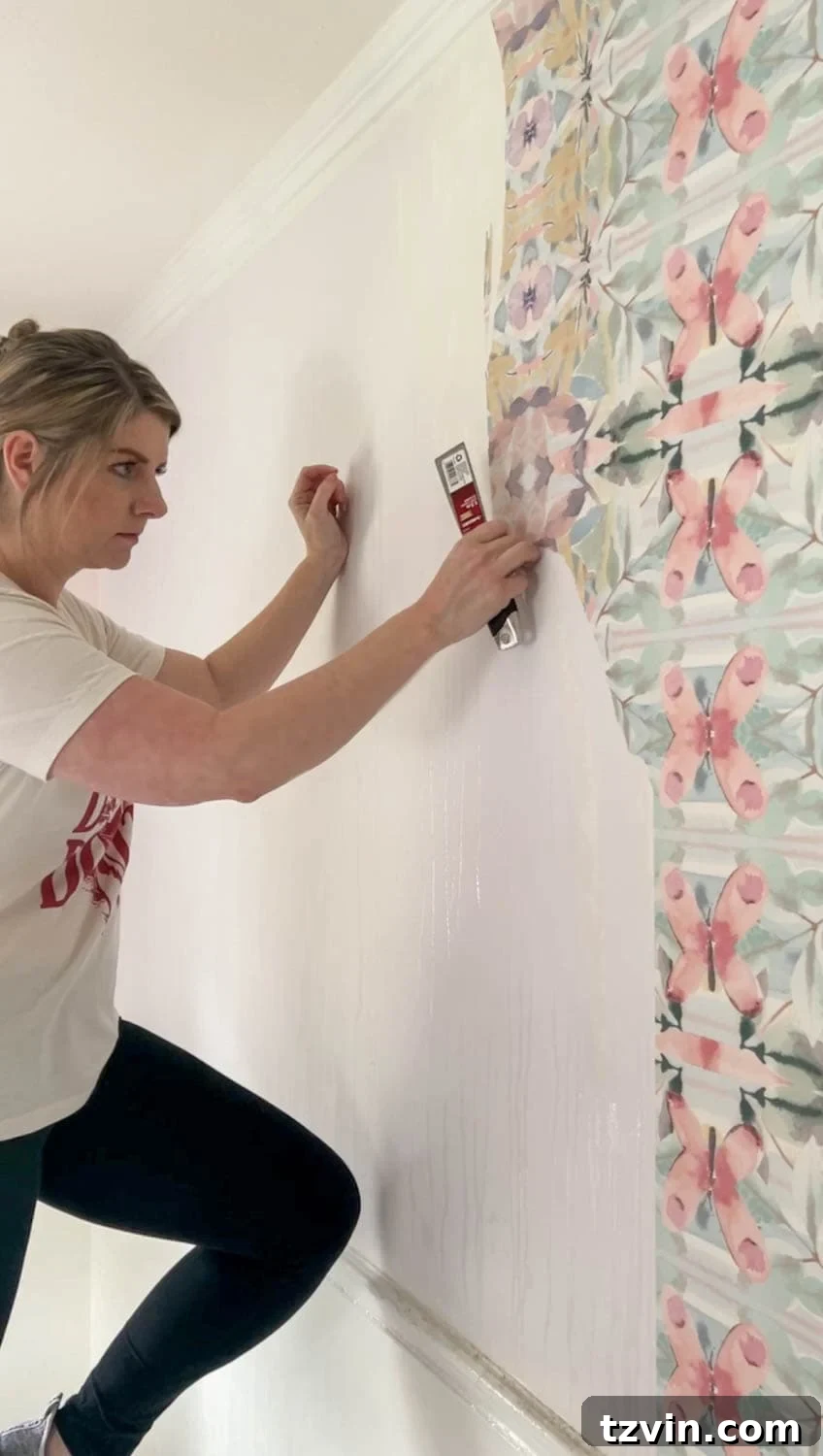 Using a putty knife to loosen wallpaper after applying vinegar solution