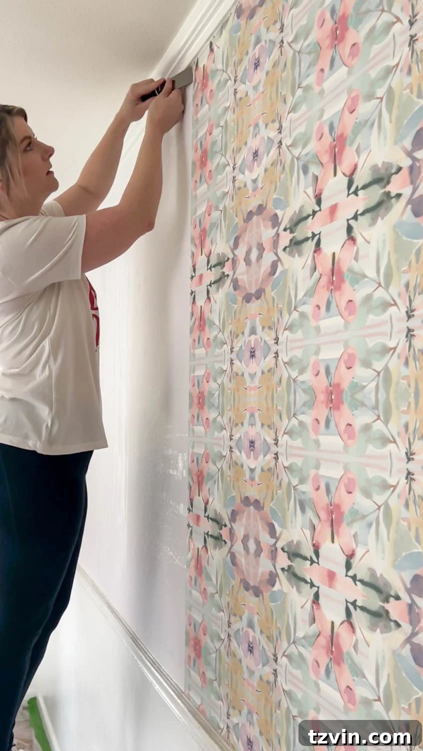 Using a putty knife to loosen edges of wallpaper for removal