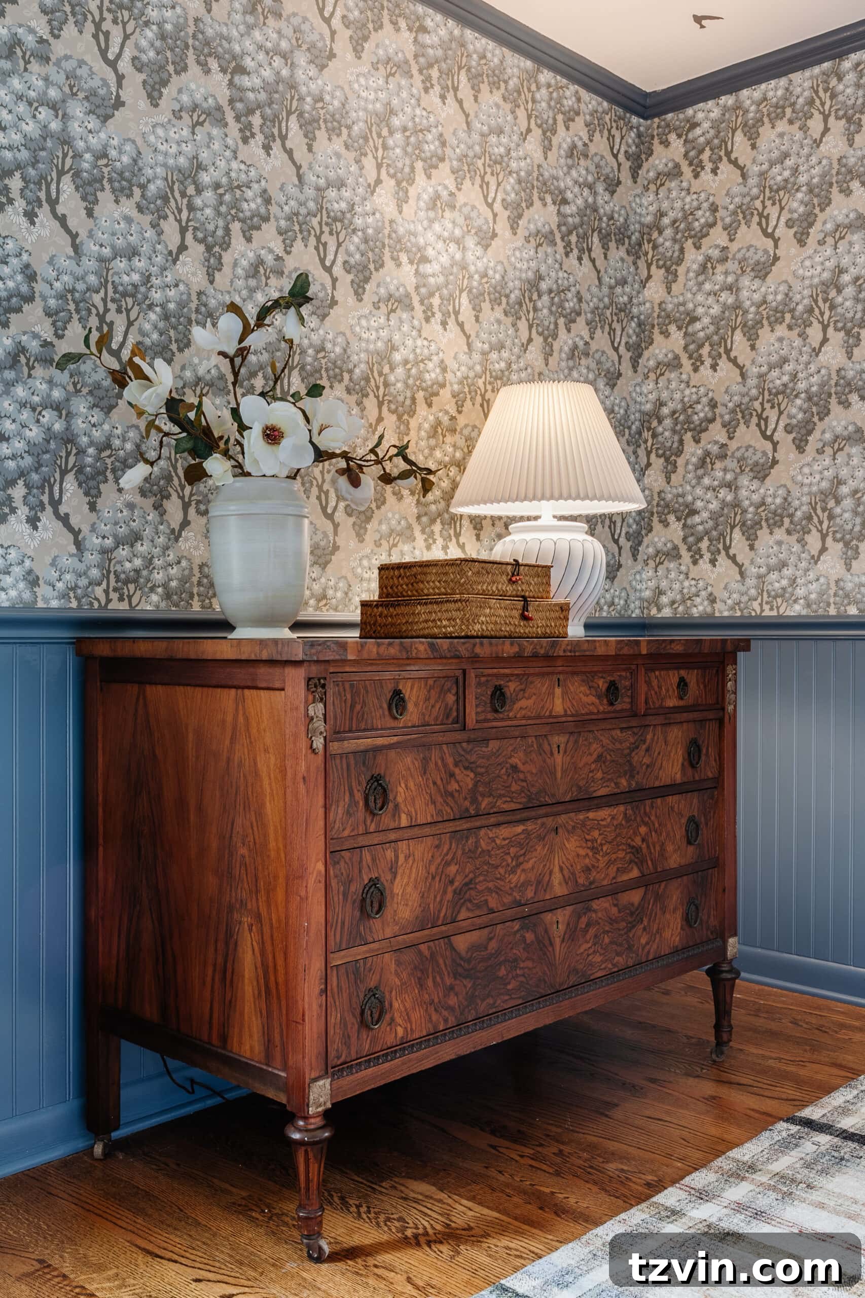 Discover Affordable Burl Wood Furniture Including Refinished Dressers 6 burl wood dresser styled with vase of flowers woven basket boxes and lamp in a bedroom with blue vintage wallpaper