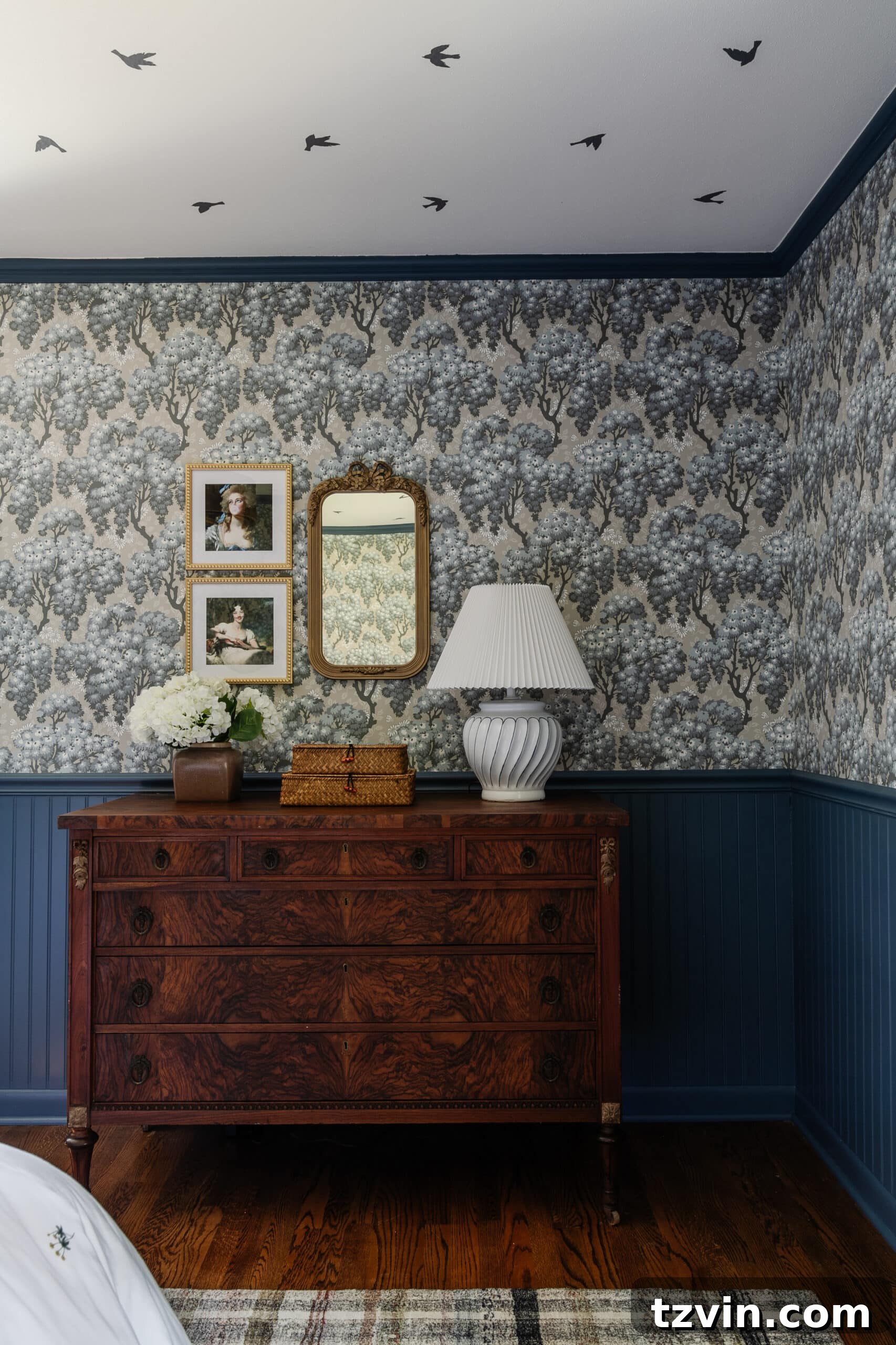 Burl wood dresser with Swedish cottage style wallpaper and gallery wall with mirror and altered portraits