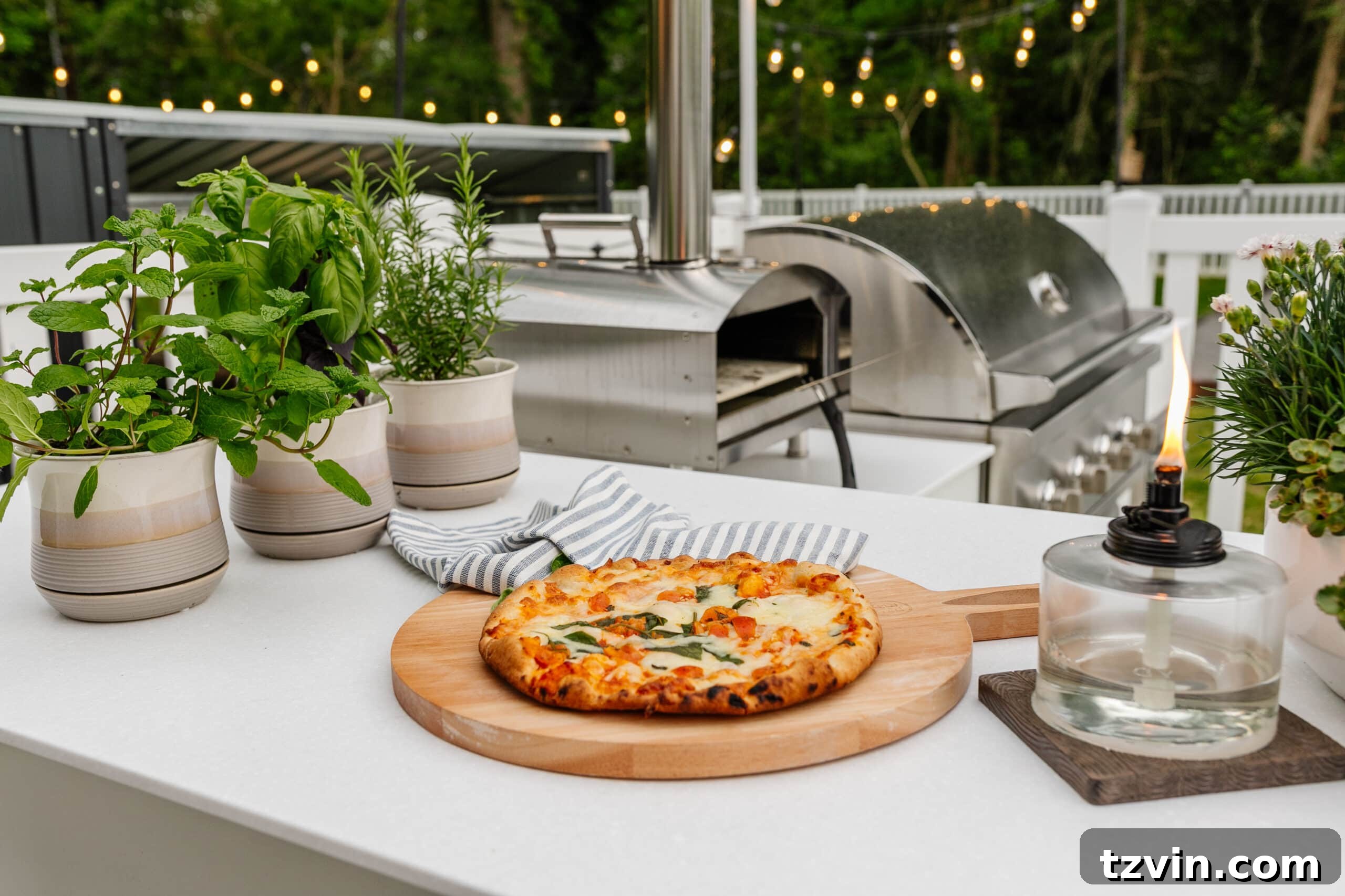 Spring Patio Refresh 13 backyard grill with outdoor pizza oven, tabletop tiki torch, and potted herbs