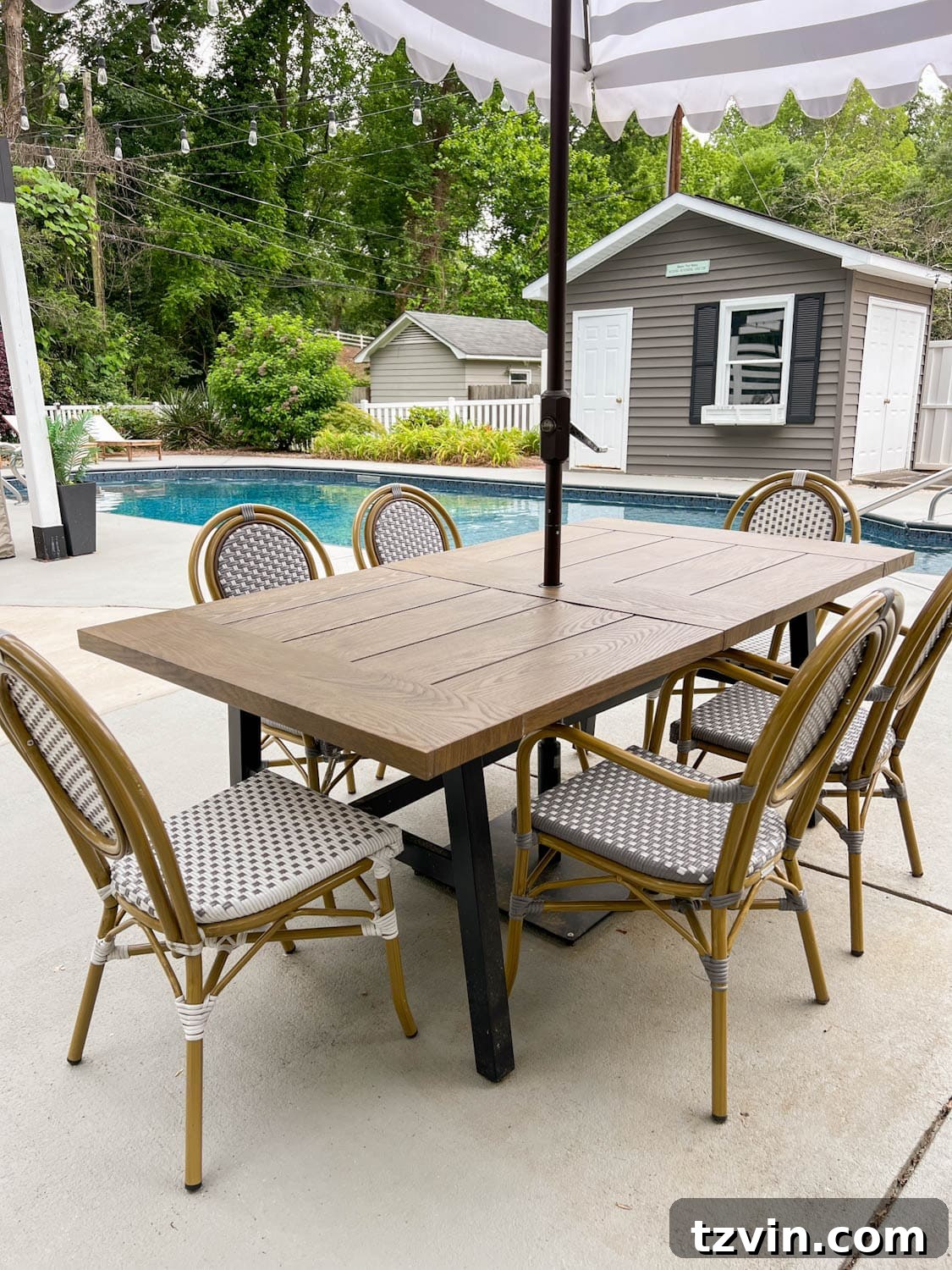 outdoor table beside a pool in a backyard with french bistro chairs
